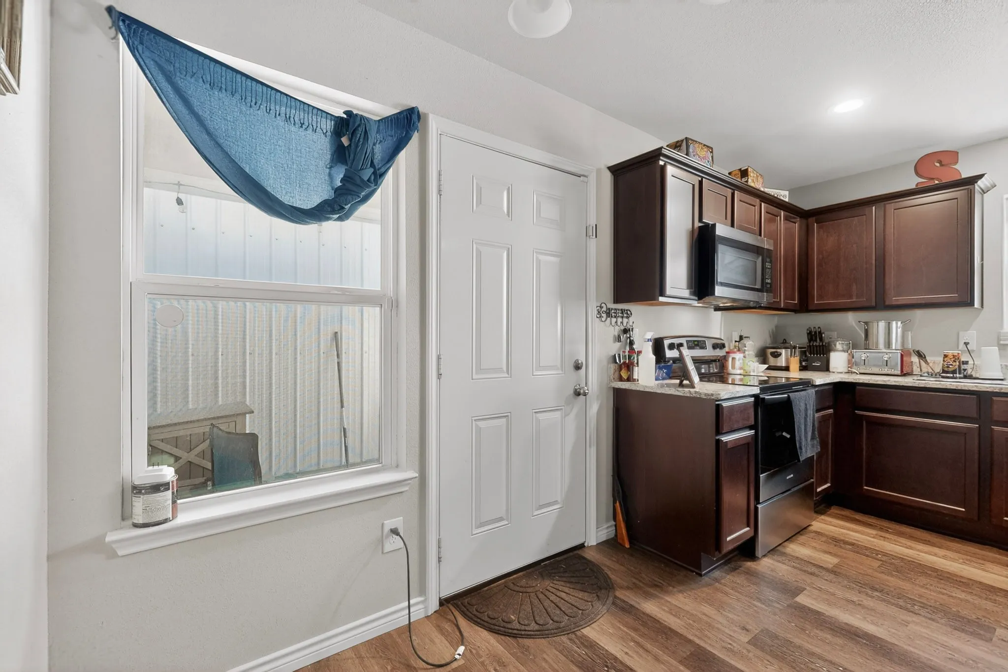 Kitchen featuring wood-finish flooring, dark wood cabinetry, and stainless steel appliances including a range and microwave