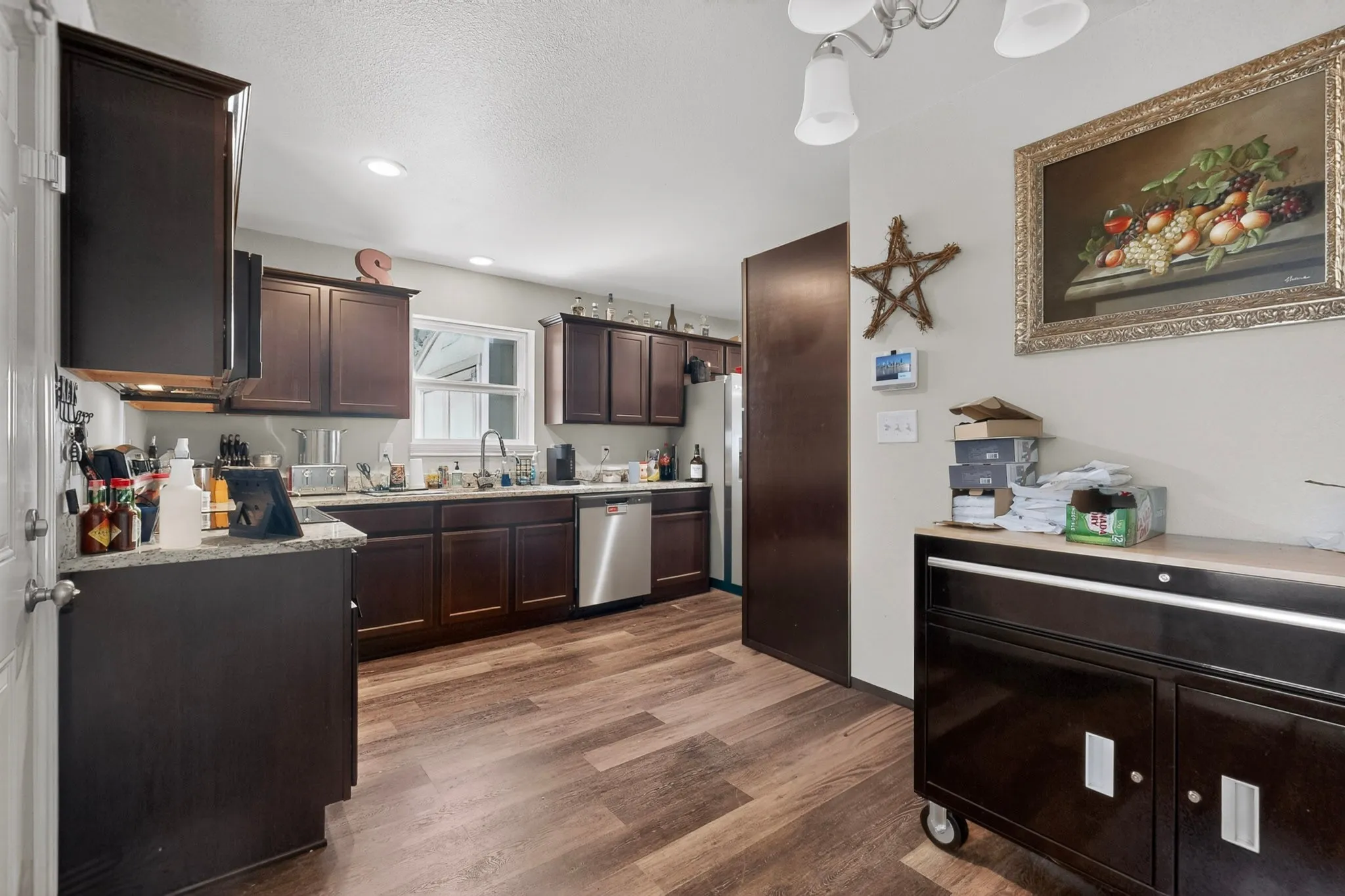 Kitchen featuring dark wood cabinetry, light-toned countertops, and wood-finish flooring