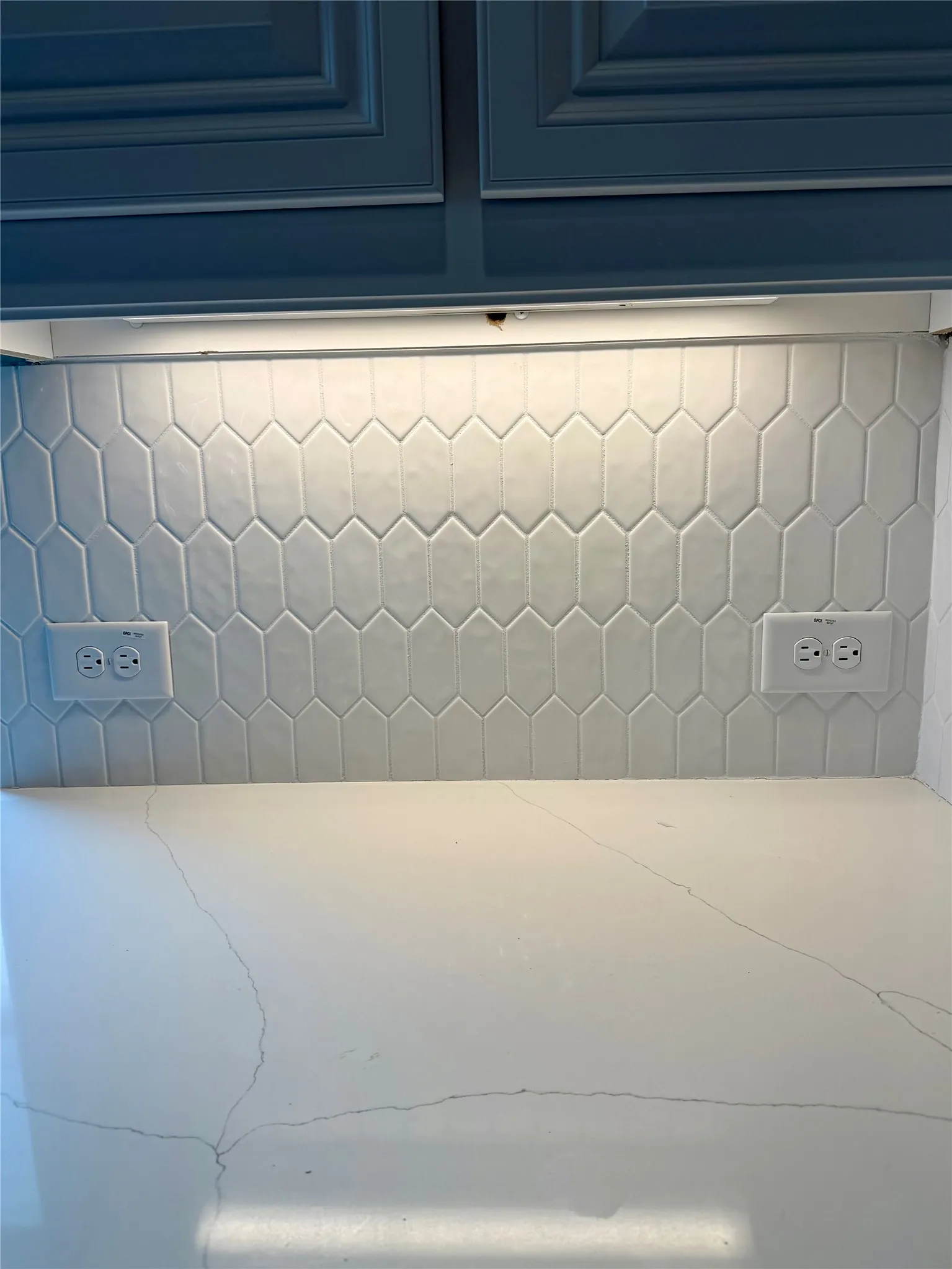 Close up of Modern picket backsplash, undercabinet lighting, White cabinets, and Lincoln quartz