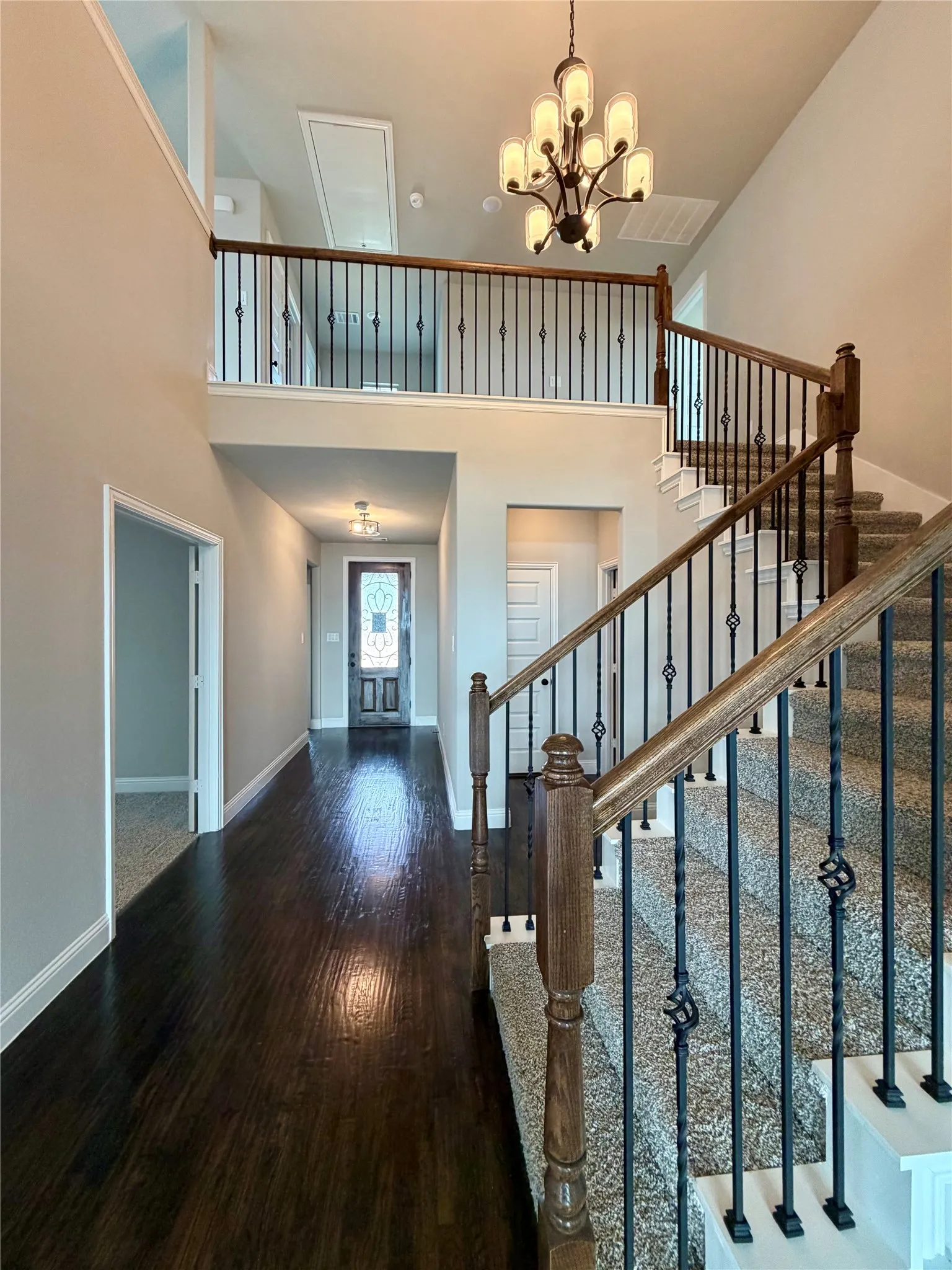Elegant stairs with cathedral ceiling,wrought iron spindles, and decorative Matte Black chandelier