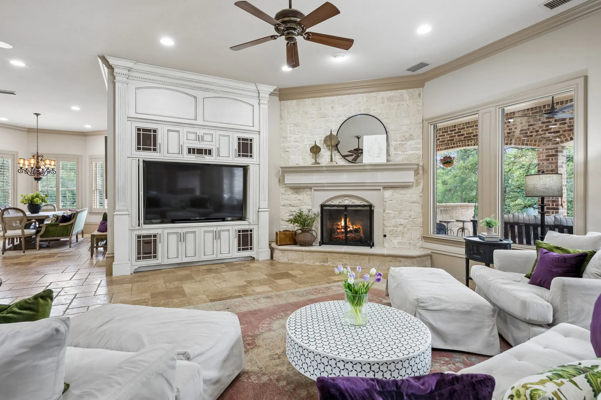 Living area featuring a stone-clad fireplace with a hearth, a custom built-in entertainment center, and two large windows
