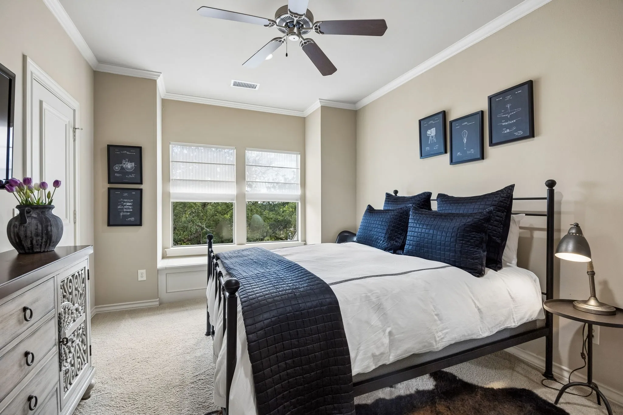 Carpeted bedroom featuring a ceiling fan, crown molding, and multiple windows with blinds