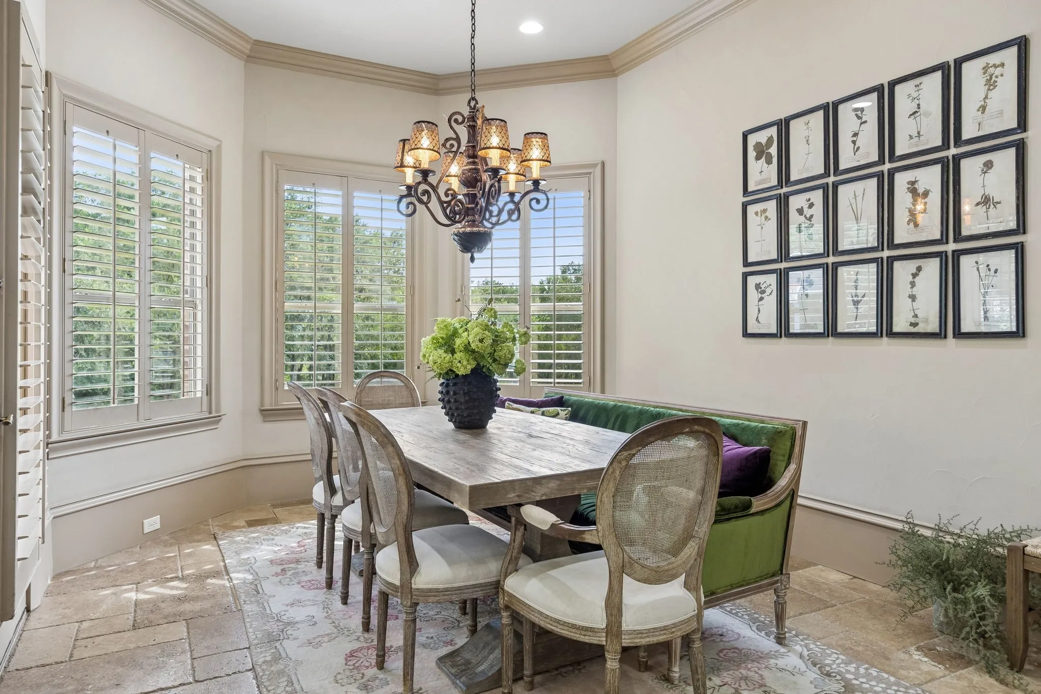 Dining space featuring an ornate chandelier, a large rectangular table, and multiple windows with plantation shutters