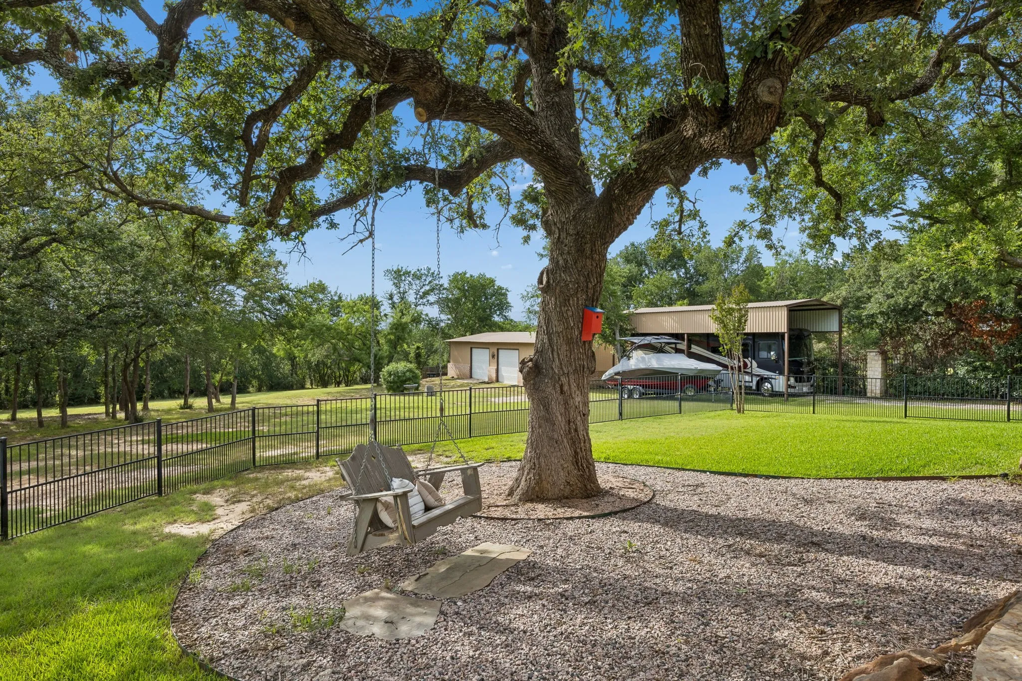 Mature tree with an expansive canopy shading a gravel patio area