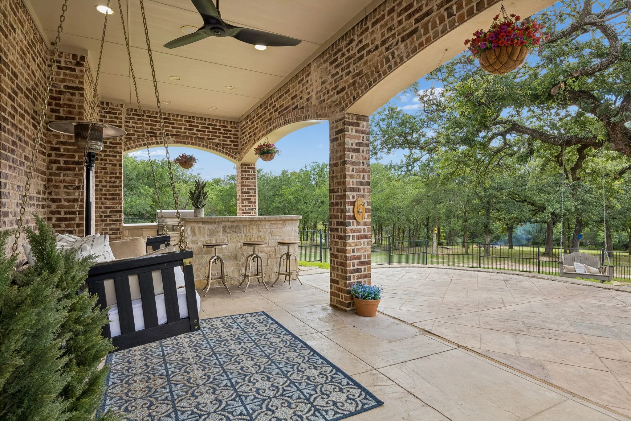 Covered outdoor patio featuring brick pillars, arched openings, and a ceiling fan