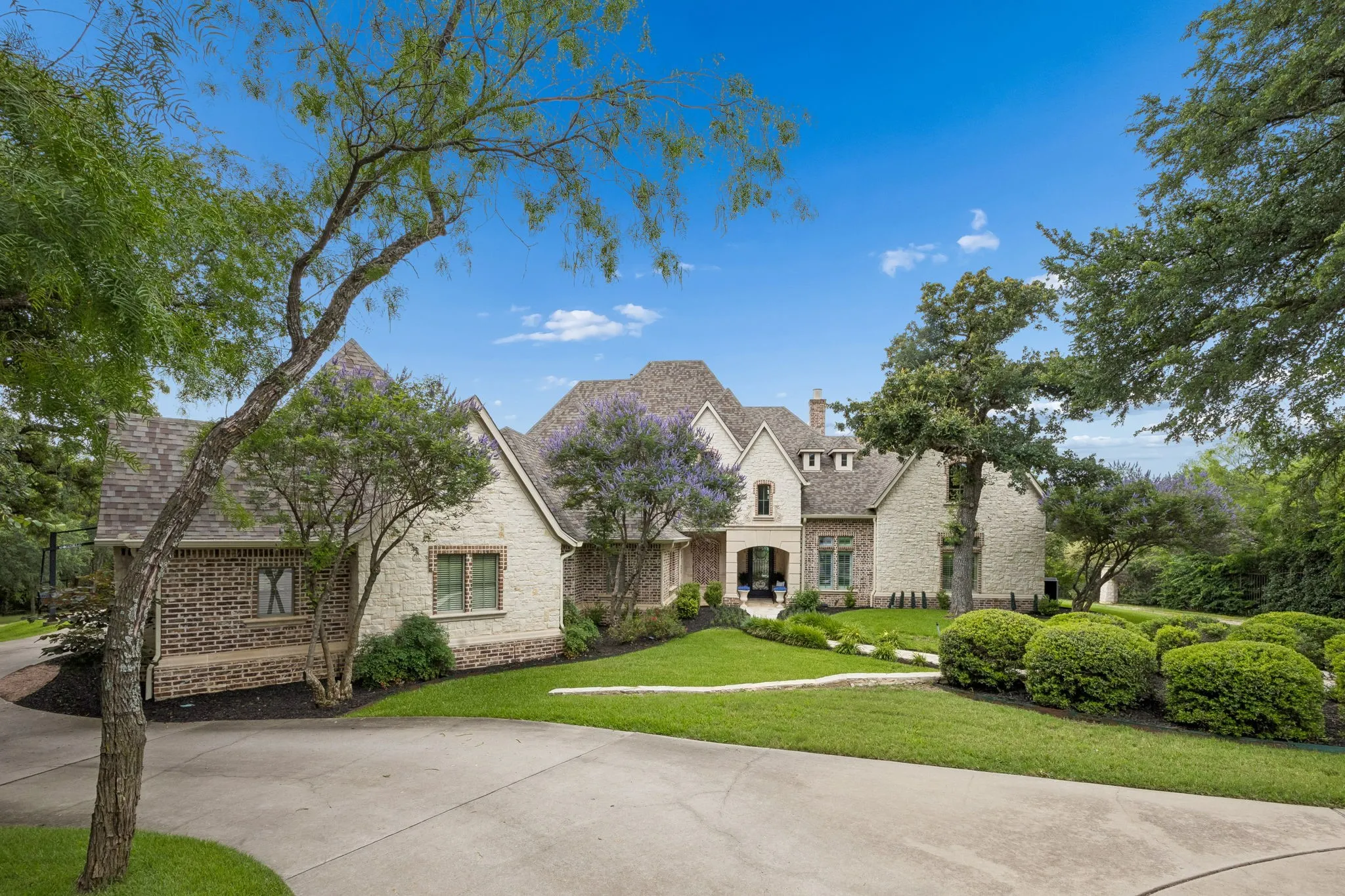 Traditional-style residence featuring a multi-gabled roofline and a combination of brick and stone facade