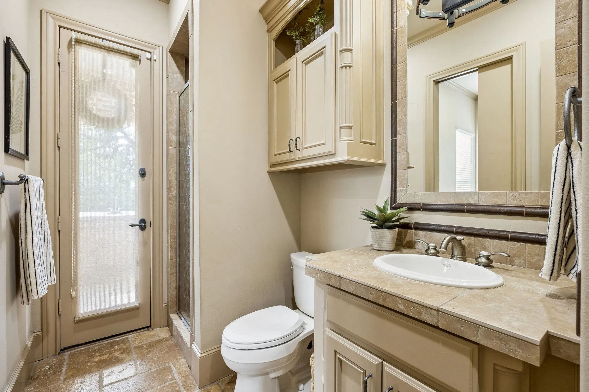 Bathroom featuring a single vanity with built-in cabinetry, tiled countertop, and an integrated sink