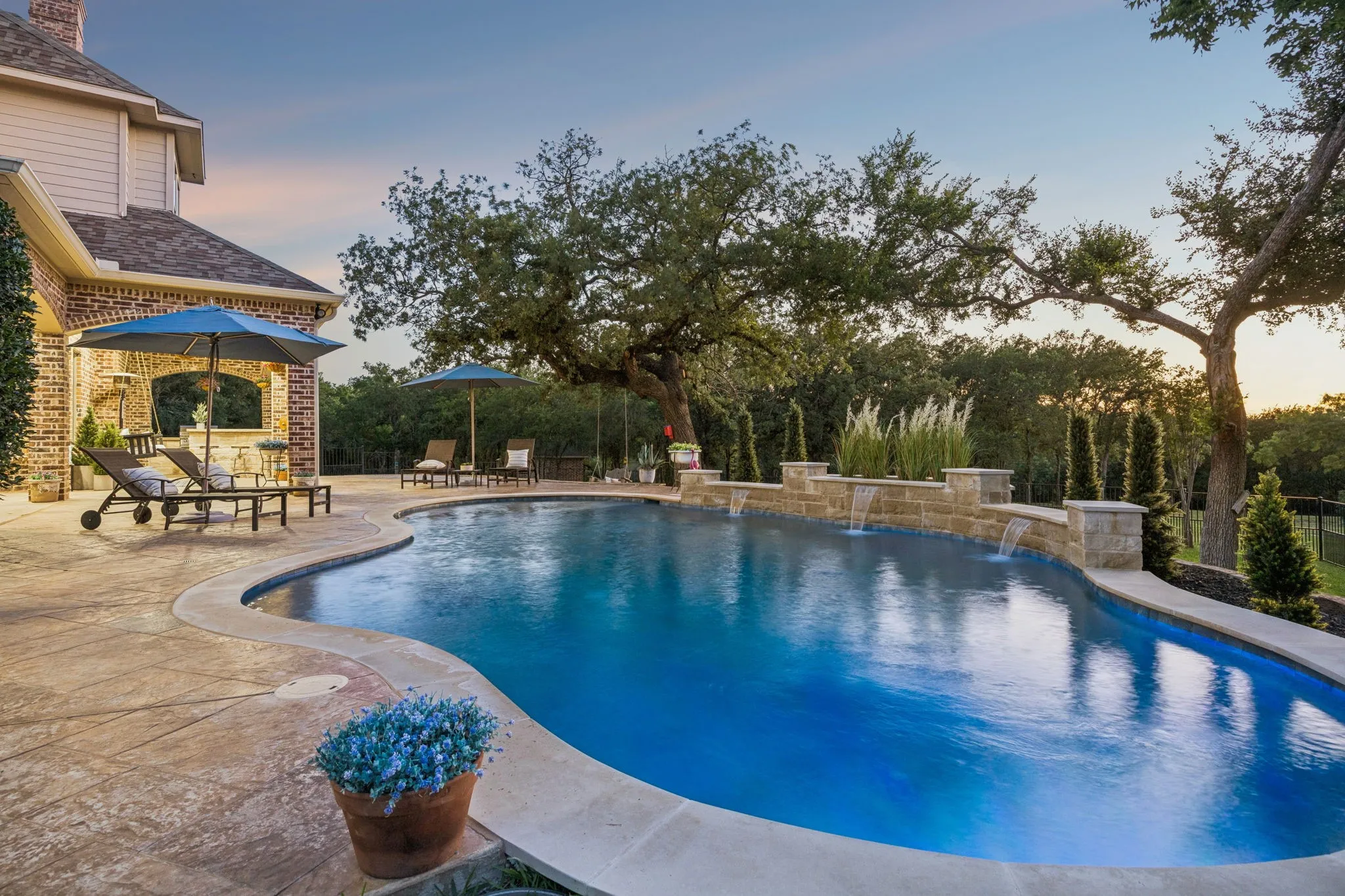 Freeform swimming pool with stone coping and multiple water features