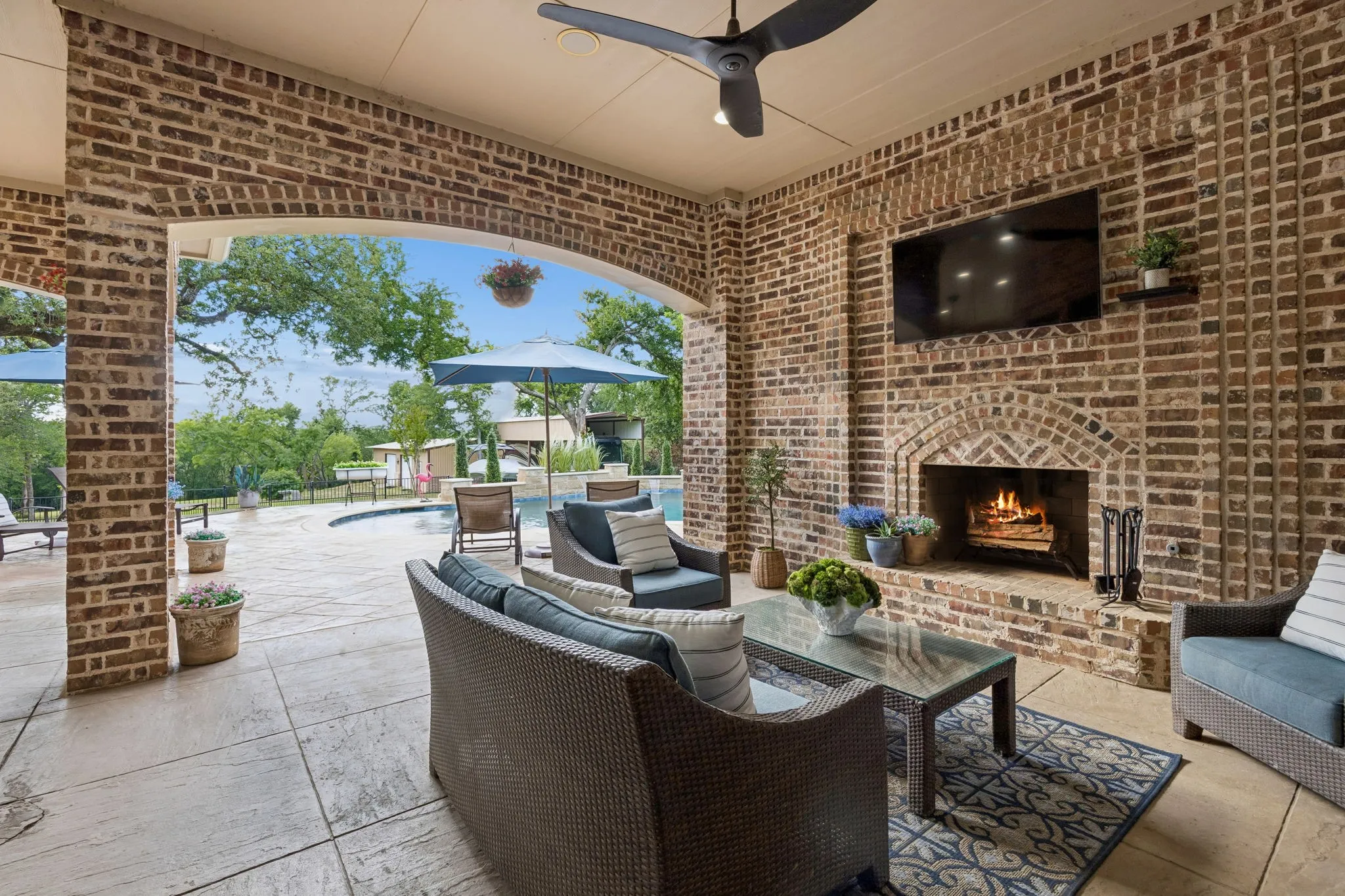 Covered patio with a brick fireplace and mounted television