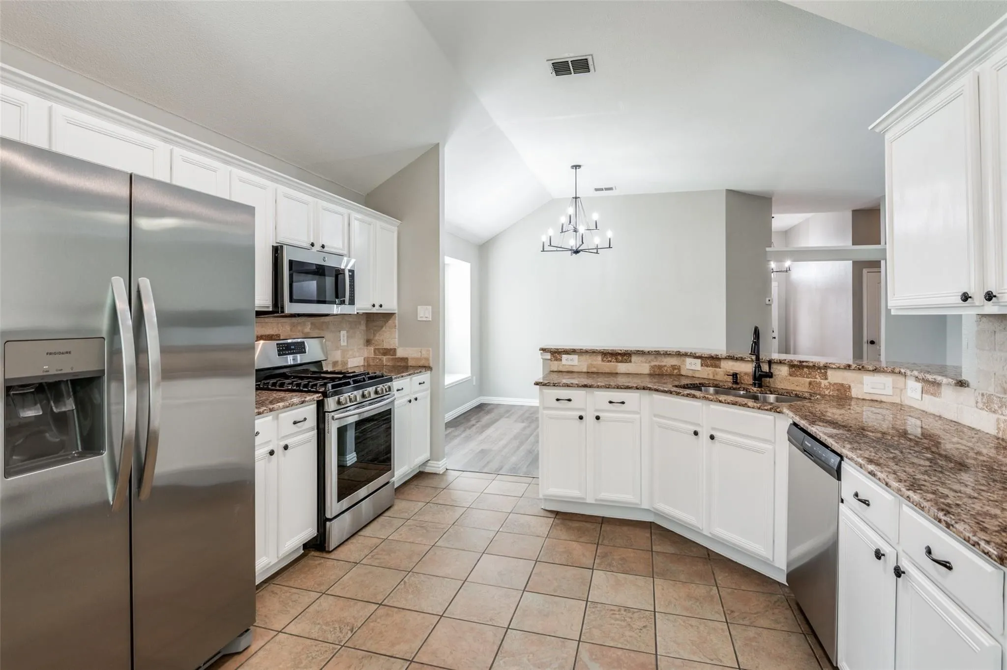 Kitchen featuring white cabinetry, stainless steel appliances, granite-style countertops, and a tile backsplash