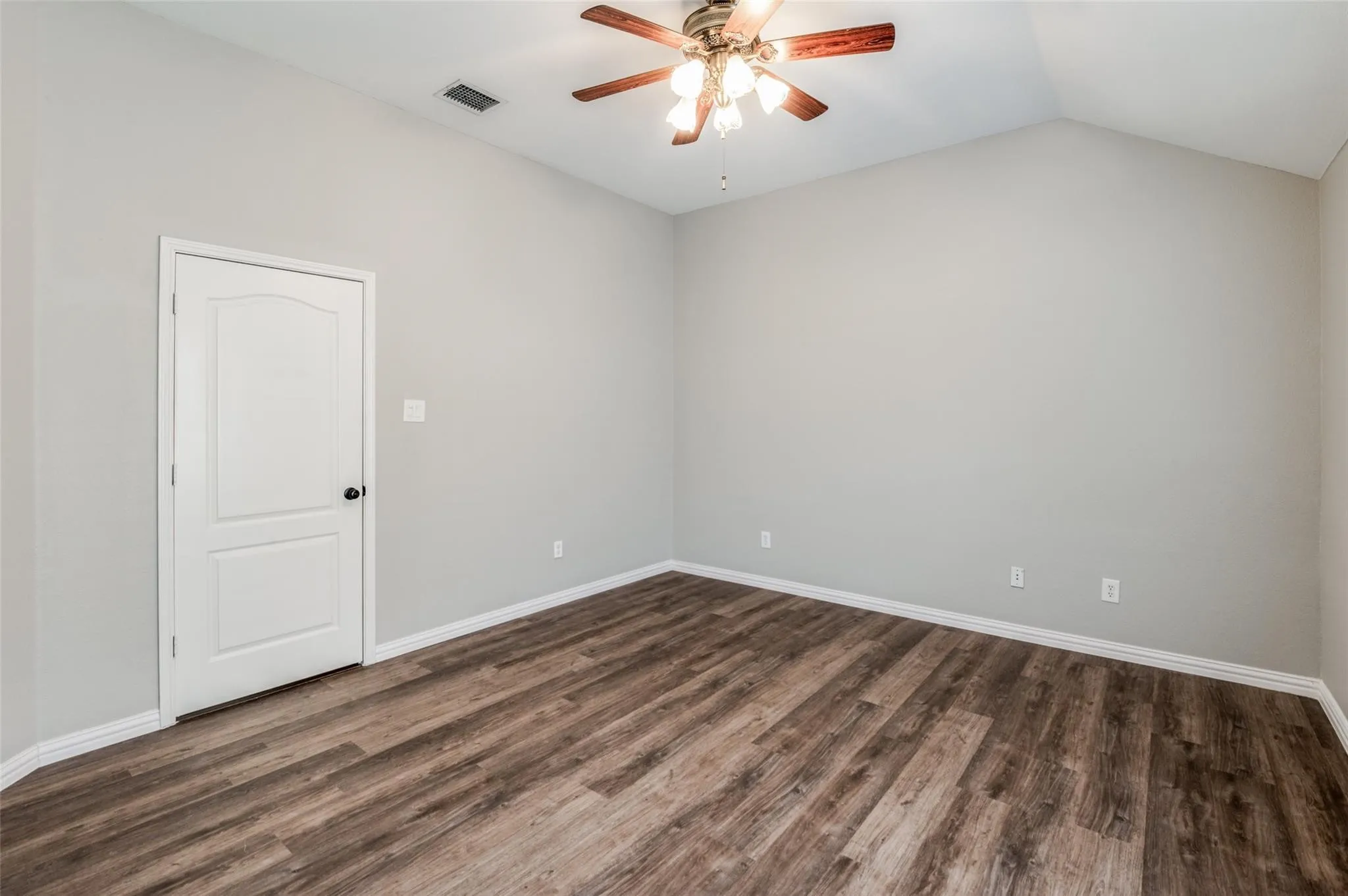 Room featuring wood-finish flooring, vaulted ceiling, and a multi-light ceiling fan