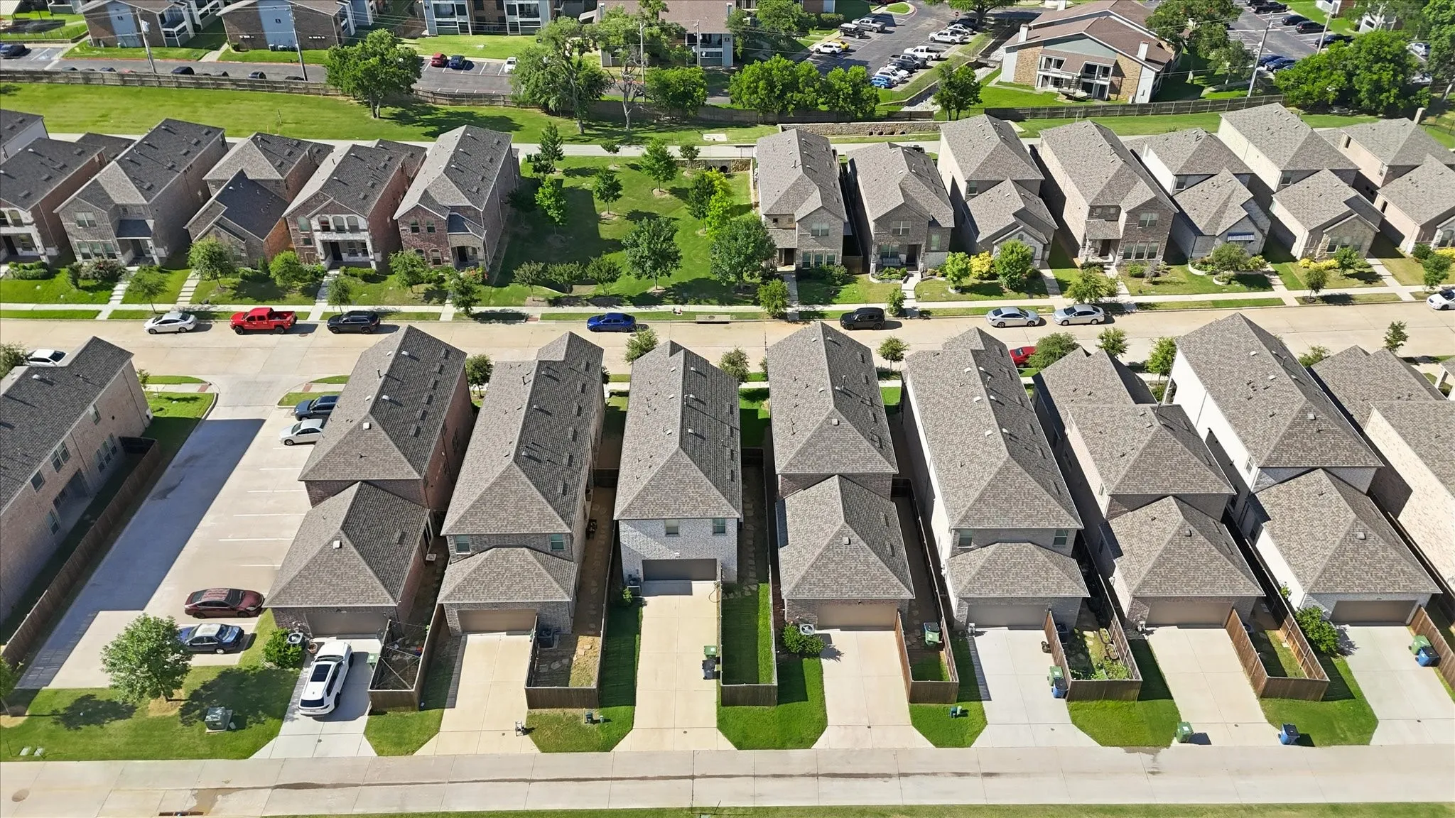 Suburban residential street with uniform single-family homes featuring attached garages and private driveways