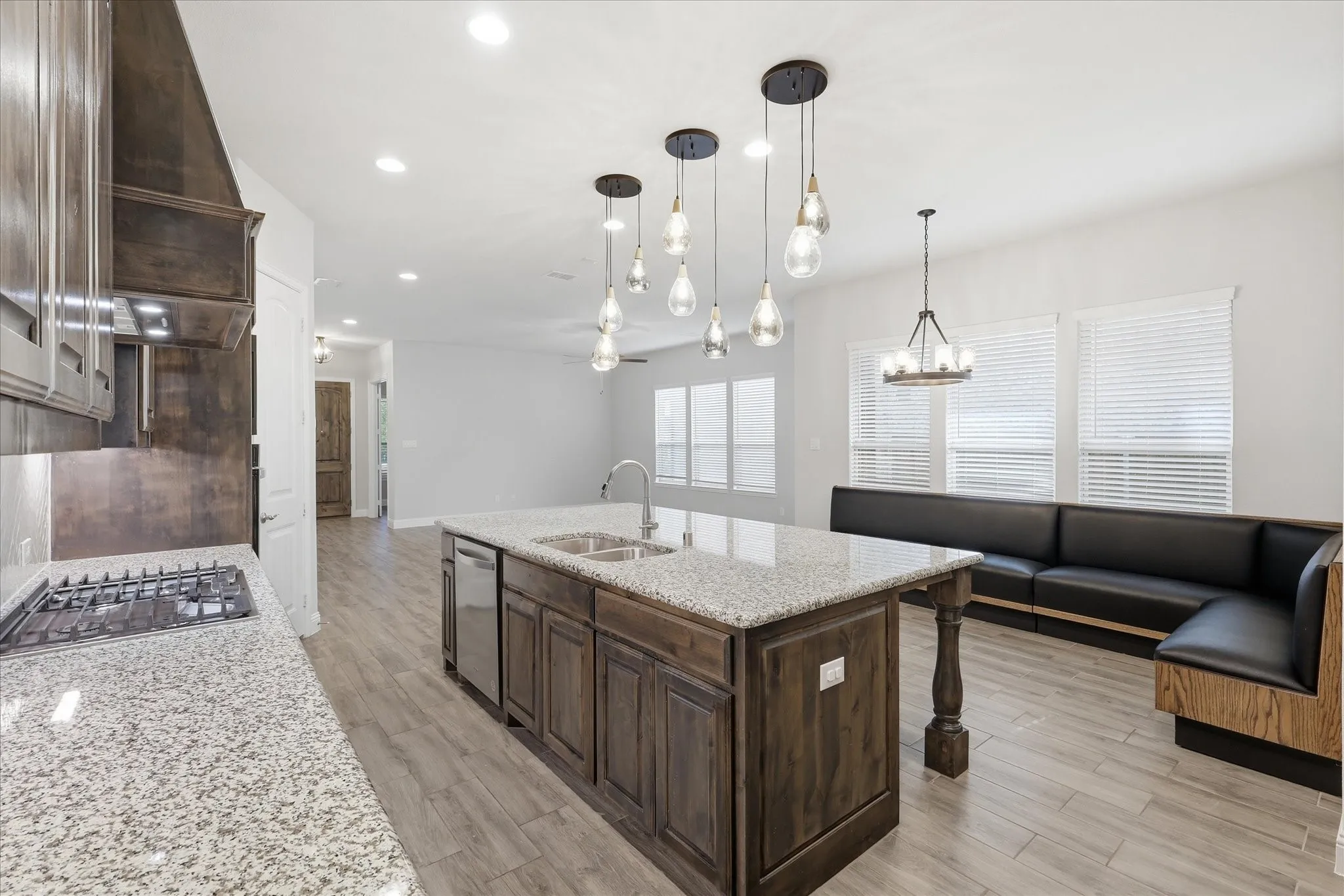 Open-concept kitchen featuring an oversized island with granite countertops, a built-in stainless steel dishwasher, and a double basin sink