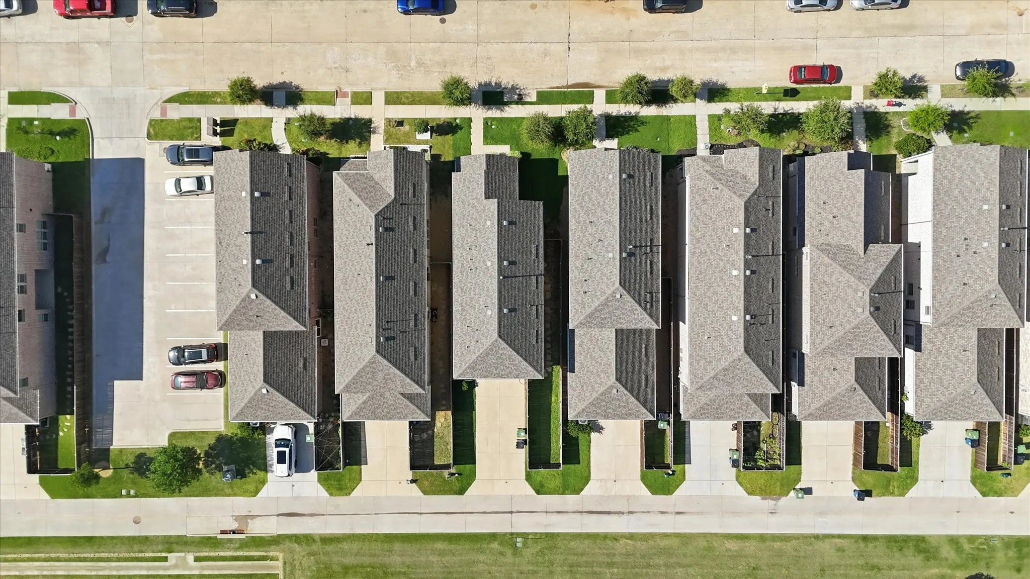 Aerial perspective showcasing a row of townhomes with pitched roofs, individual driveways, and manicured green spaces