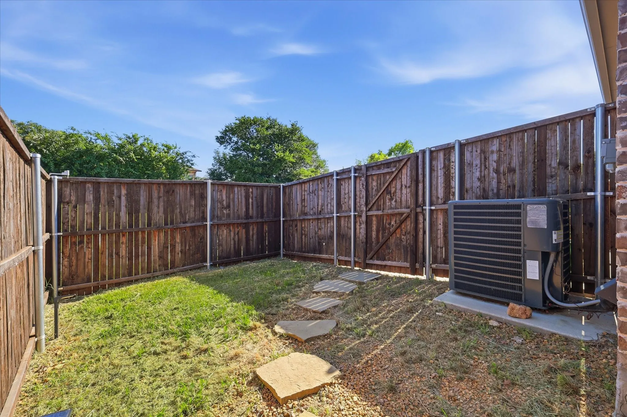 Private backyard space featuring a wood privacy fence with metal posts, a gate, and stone paver accents