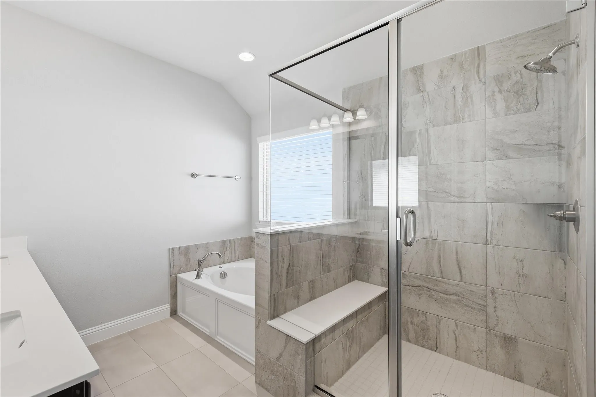Bathroom featuring a walk-in shower with a built-in bench, a separate soaking tub, and a vanity with a single sink