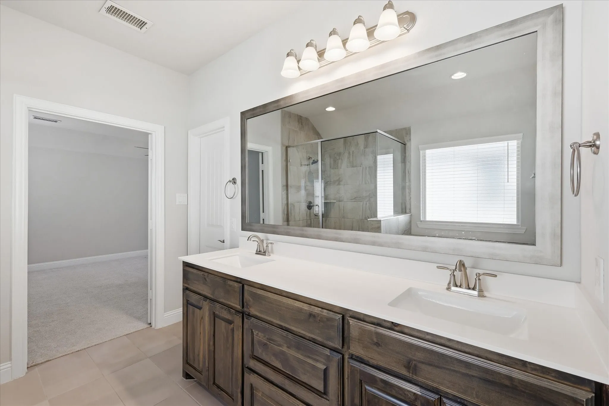 Dual vanity with undermount sinks, stone-finish countertop, and wood-finish cabinetry