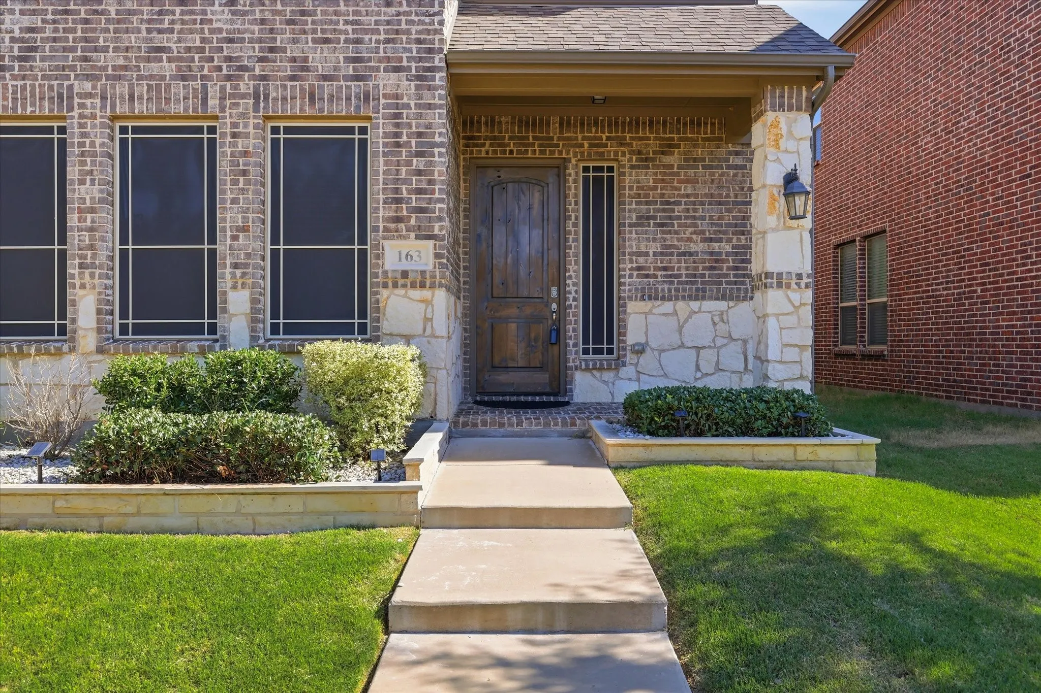 Brick and stone facade featuring a wood-grain entry door and covered porch
