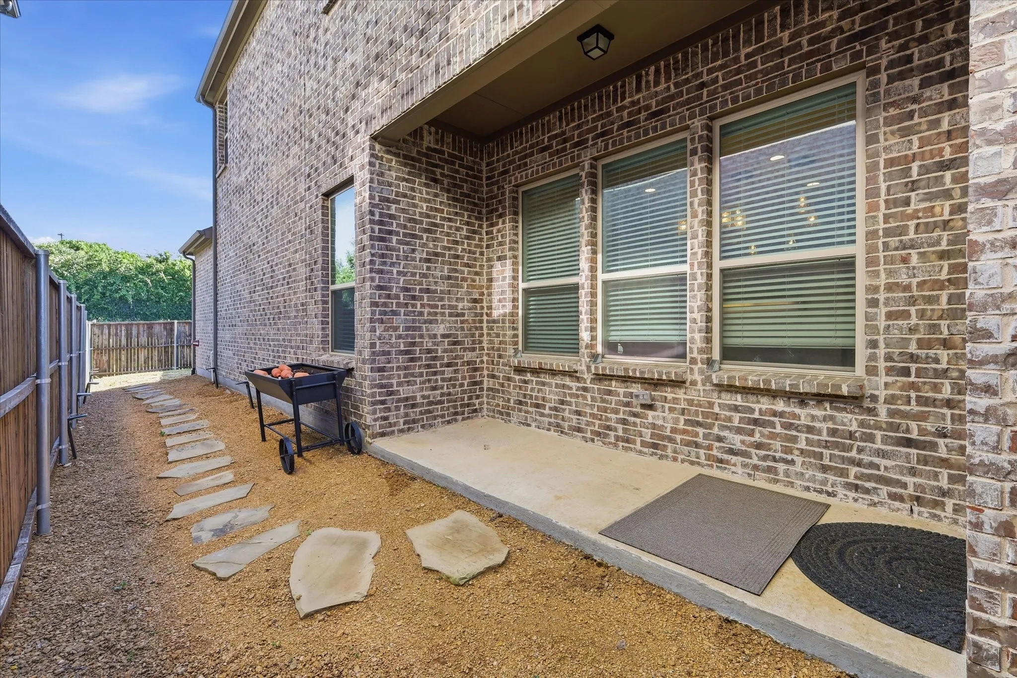 Side yard featuring a gravel pathway, stone stepping pads, and a privacy fence