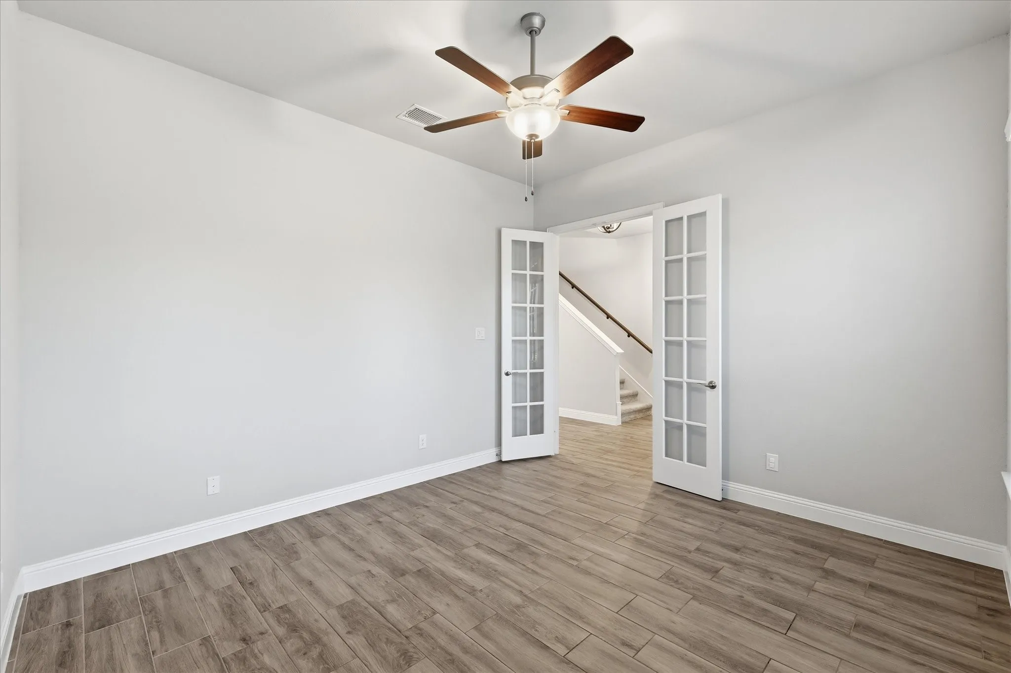 Room with wood-finish flooring, light grey walls, and white baseboards