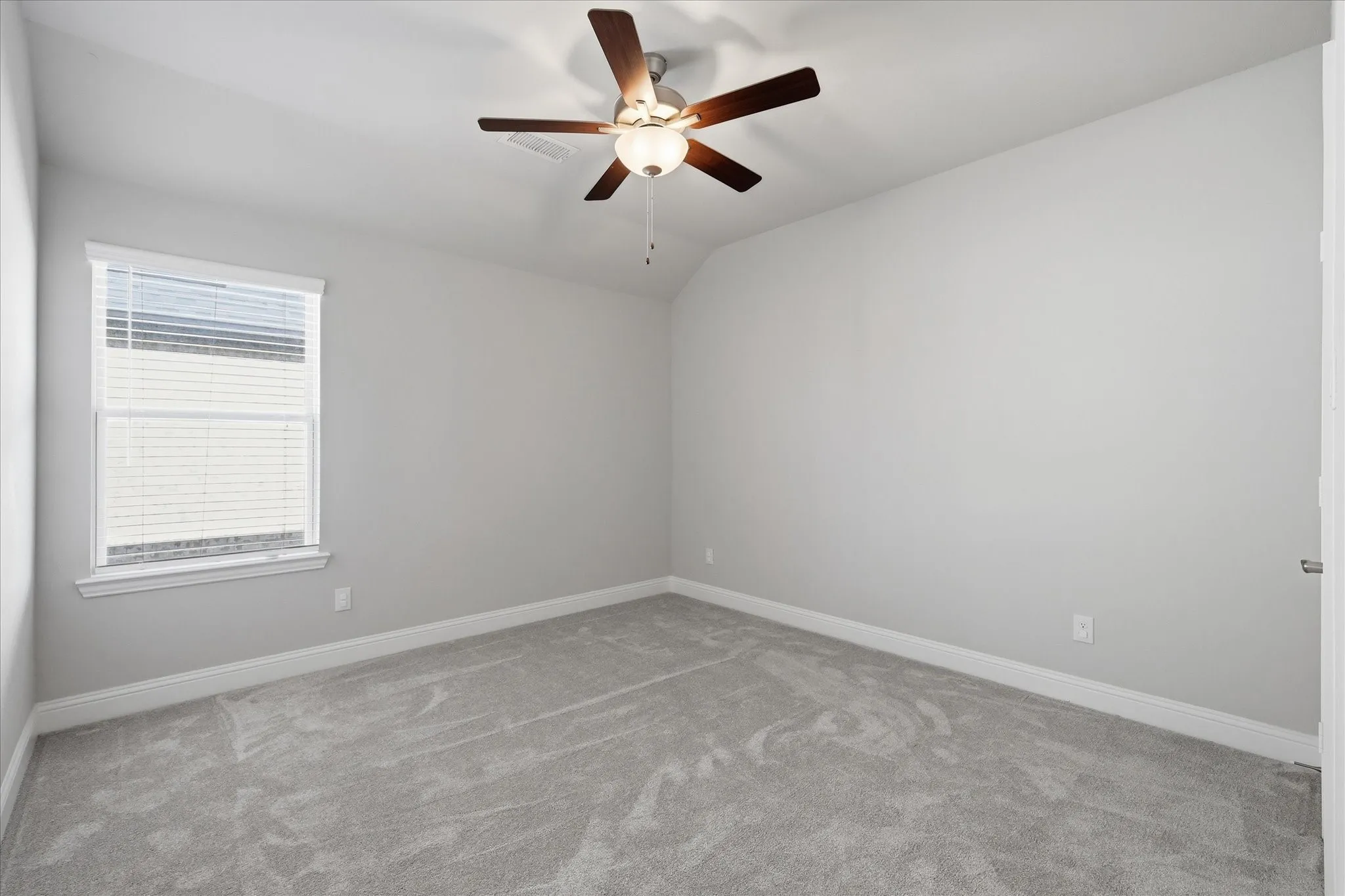 Carpeted room featuring a ceiling fan with light fixture, window with blinds, and white baseboards