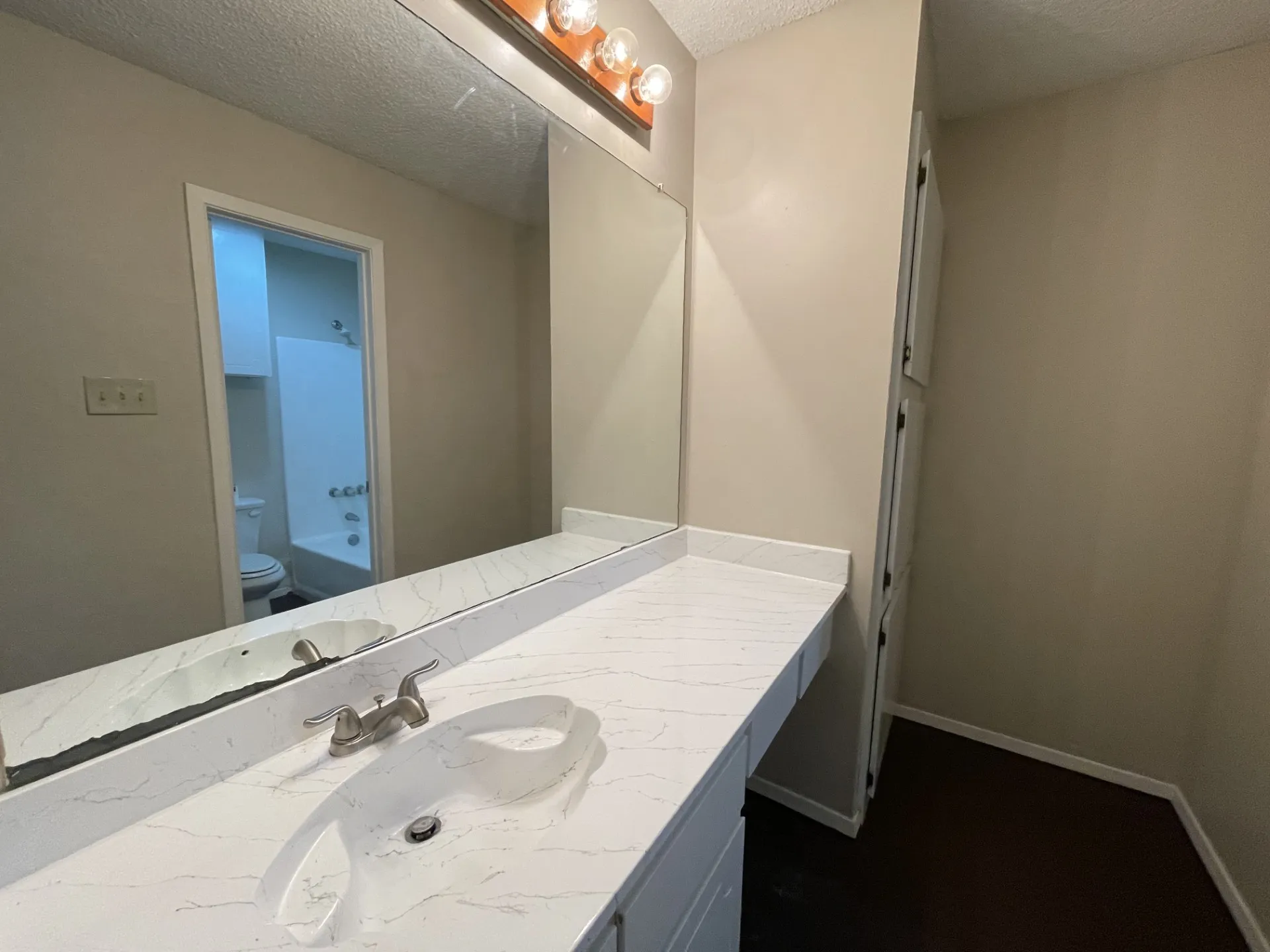 Bathroom vanity featuring a single basin sink, white countertop, and built-in cabinetry