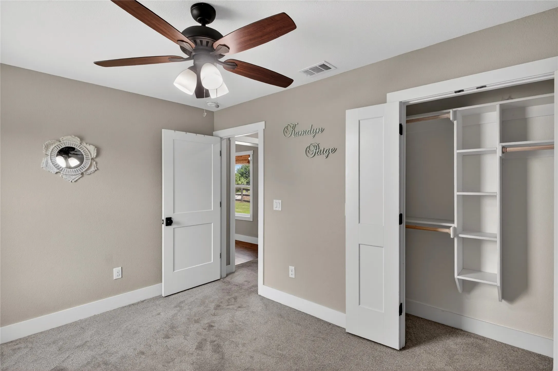 Bedroom featuring plush gray carpeting, a multi-speed ceiling fan with integrated lighting, and a closet with custom built-in shelving and hanging rods