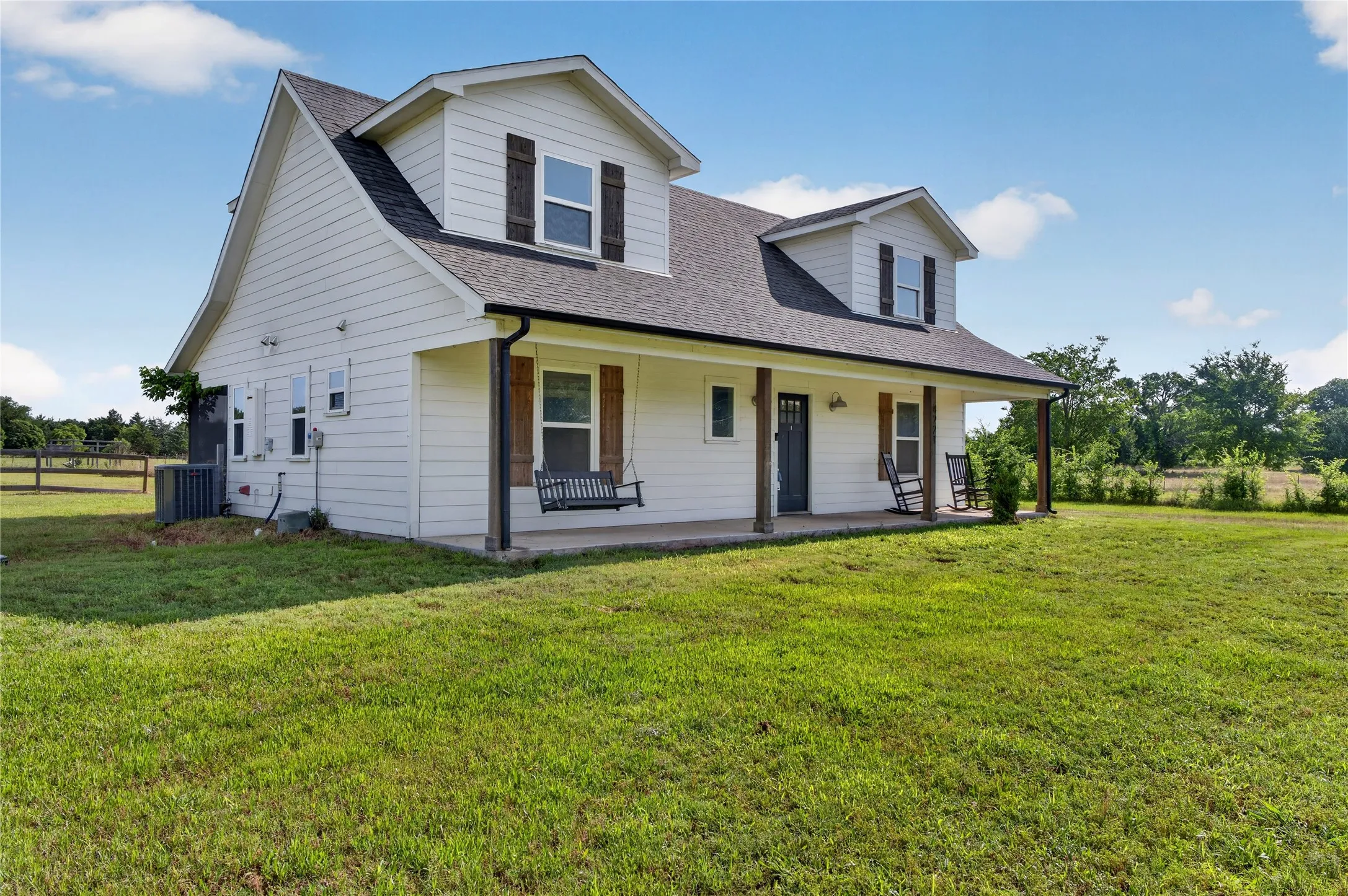 White siding residence with a covered front porch featuring dark wood columns