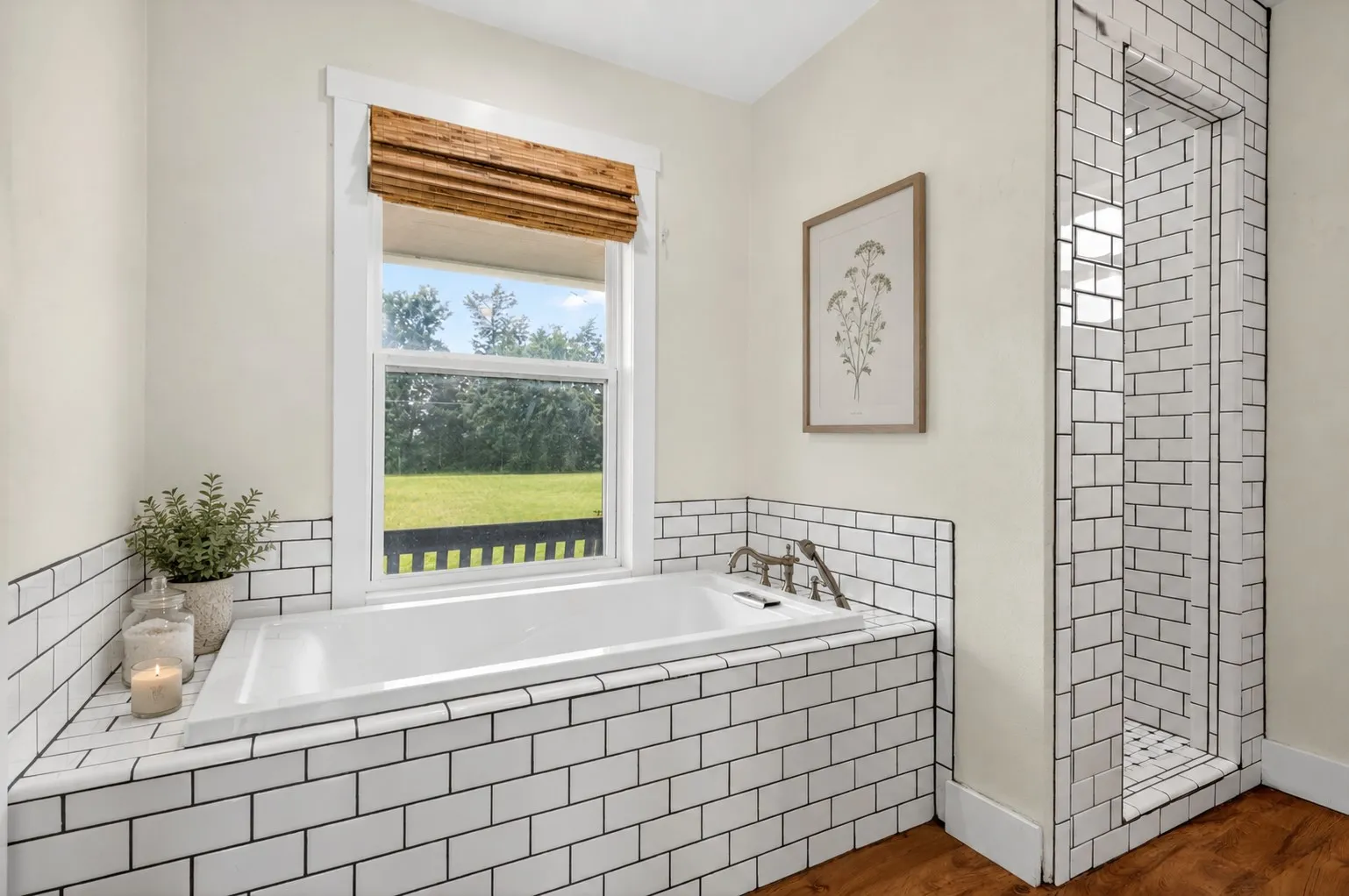 Soaking tub with subway tile surround, polished nickel fixtures, and a woven wood shade