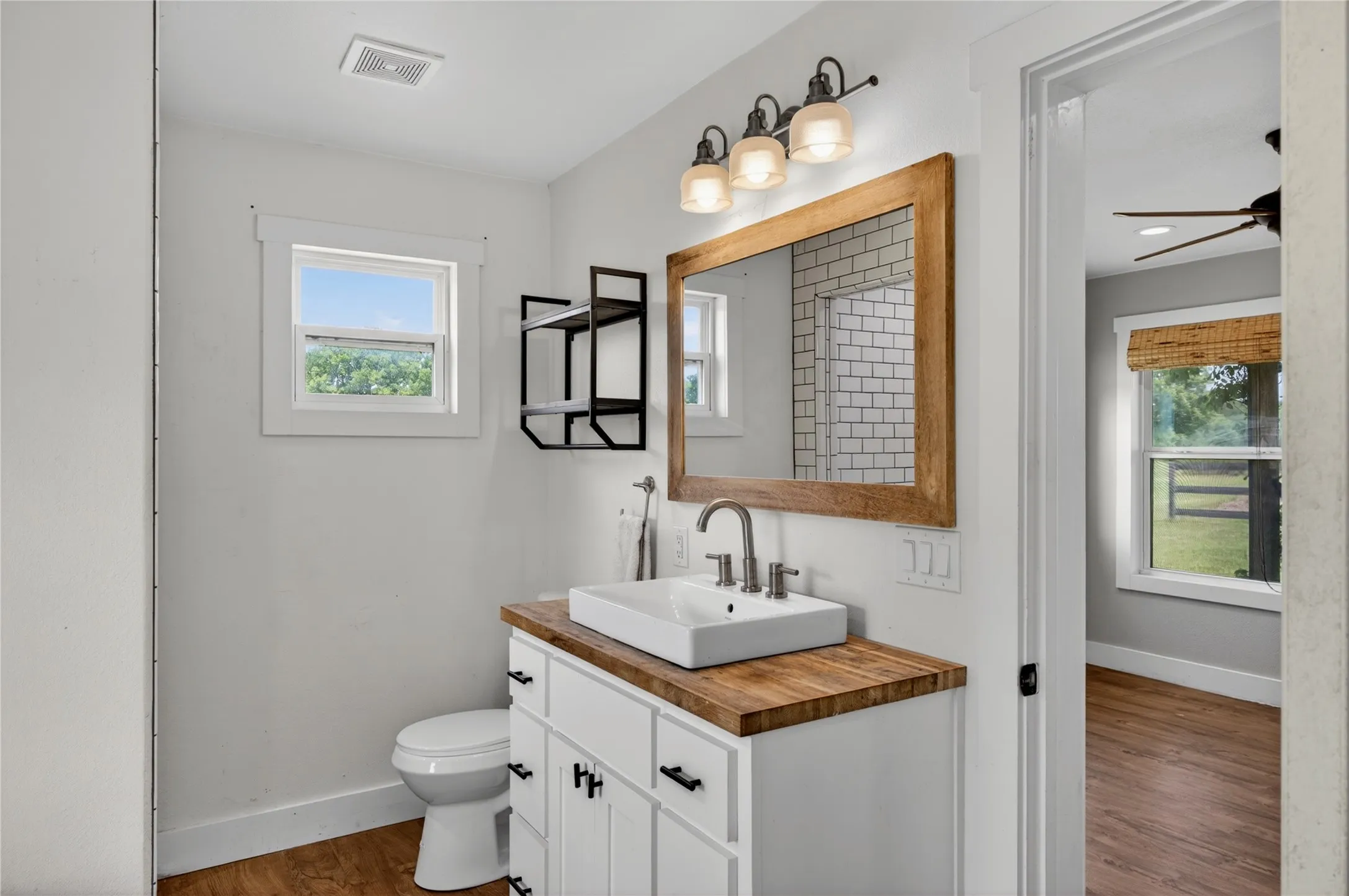 Bathroom featuring a white floating vanity with a wood-finish countertop, vessel sink, and wall-mounted faucet