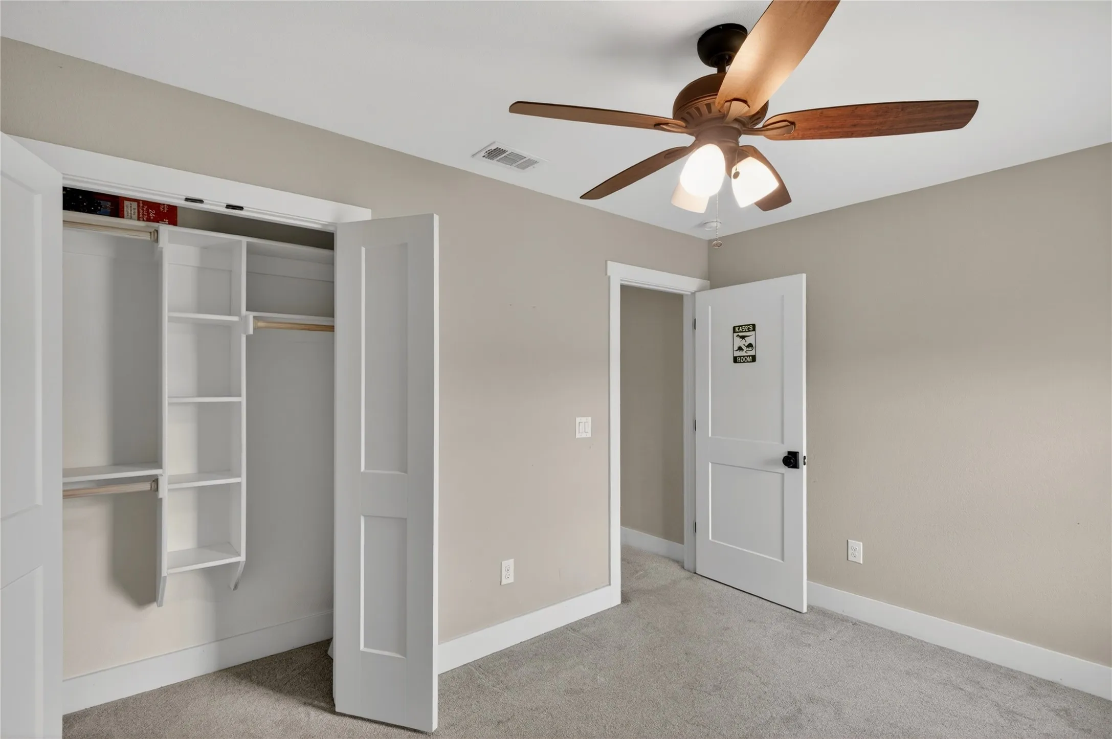 Bedroom featuring neutral wall paint, gray carpet, a ceiling fan with integrated lighting, and a closet with bifold panel doors and built-in shelving
