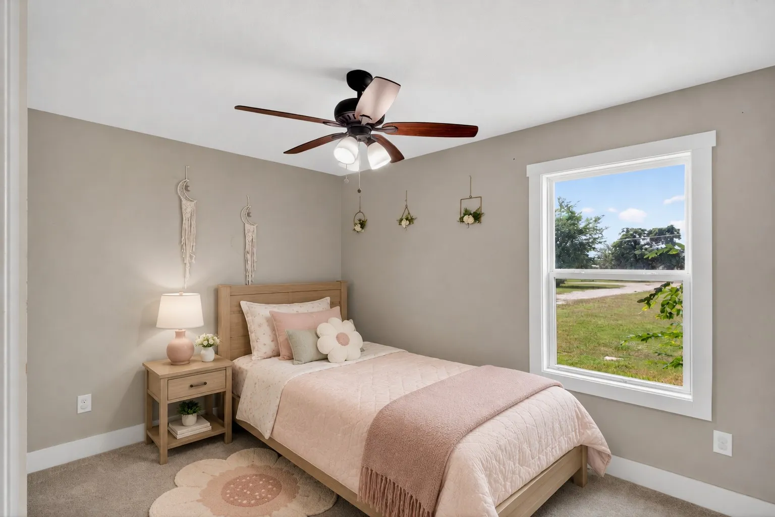 Carpeted room featuring a ceiling fan with light fixture, a single-pane window with white trim, and light beige wall paint. Some elements are virtually staged.