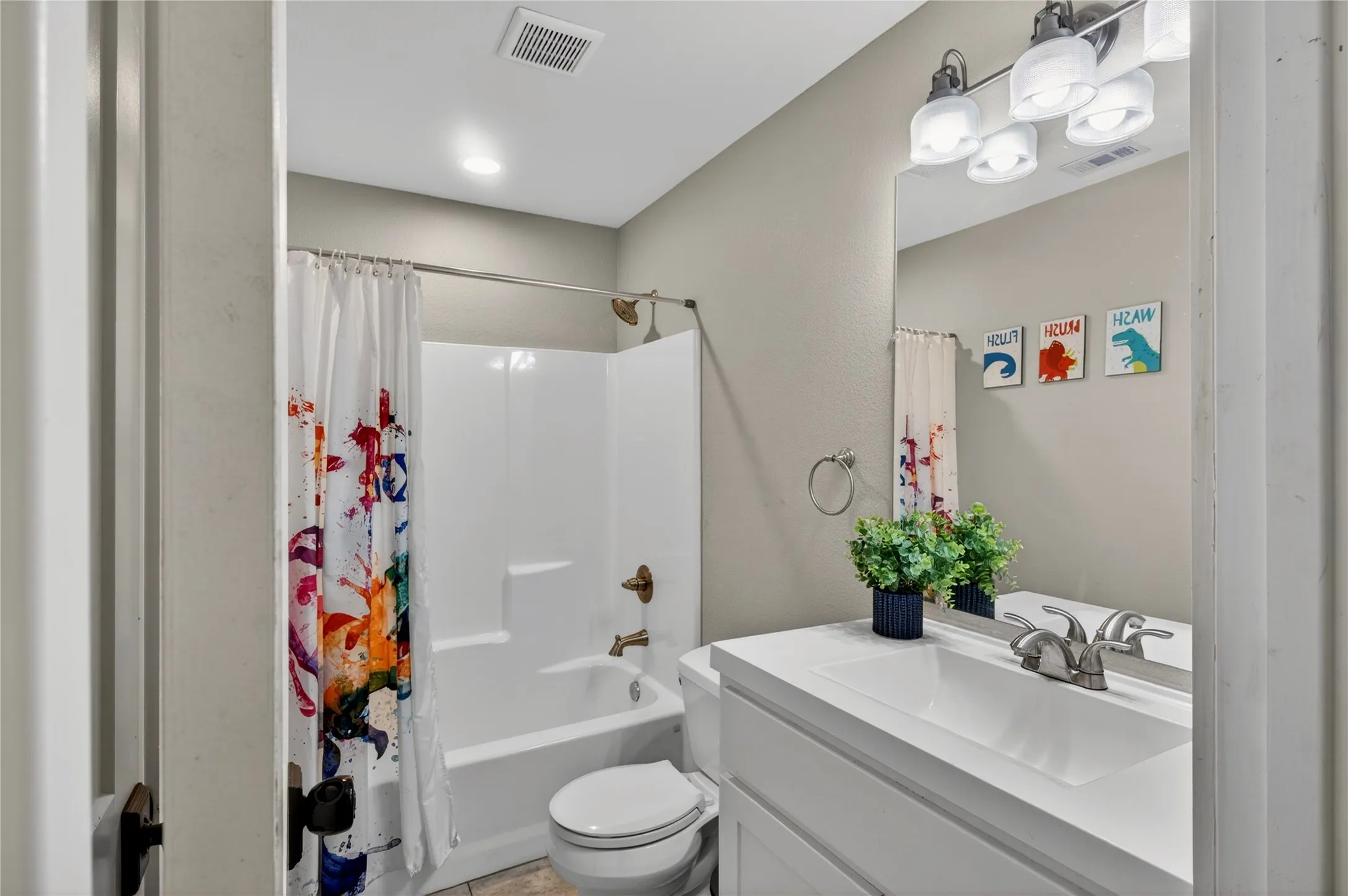 Bathroom featuring a white integrated sink vanity, wall-mounted mirror, and a full-size bathtub with an overhead shower