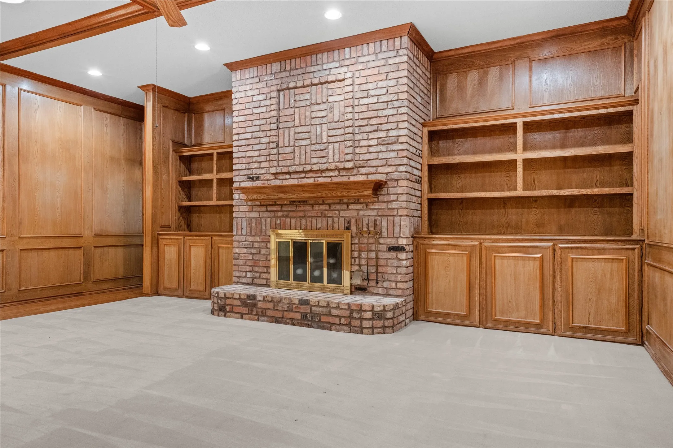 Brick fireplace with a brass-framed firebox, flanked by custom wood built-in shelving and cabinetry