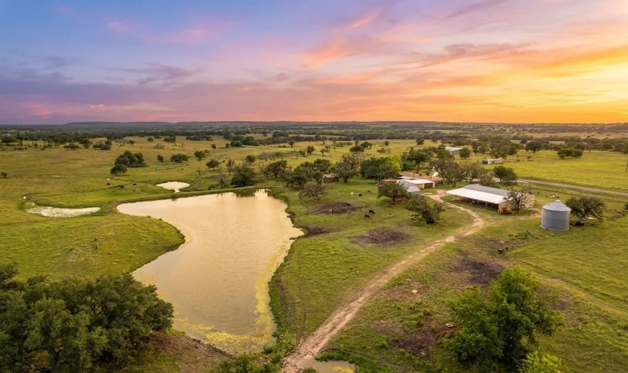 Expansive property featuring a large pond and additional smaller pond, surrounded by verdant pastures and scattered mature trees