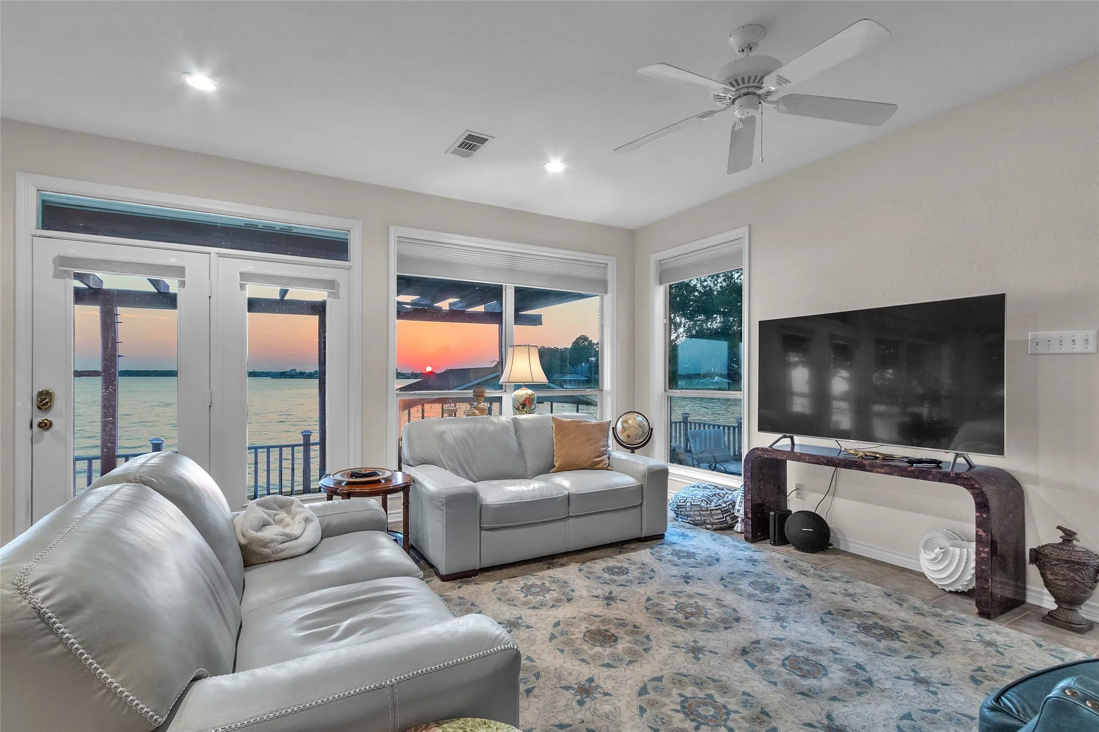Living room with plenty of natural light, ceiling fan, a water view, and french doors
