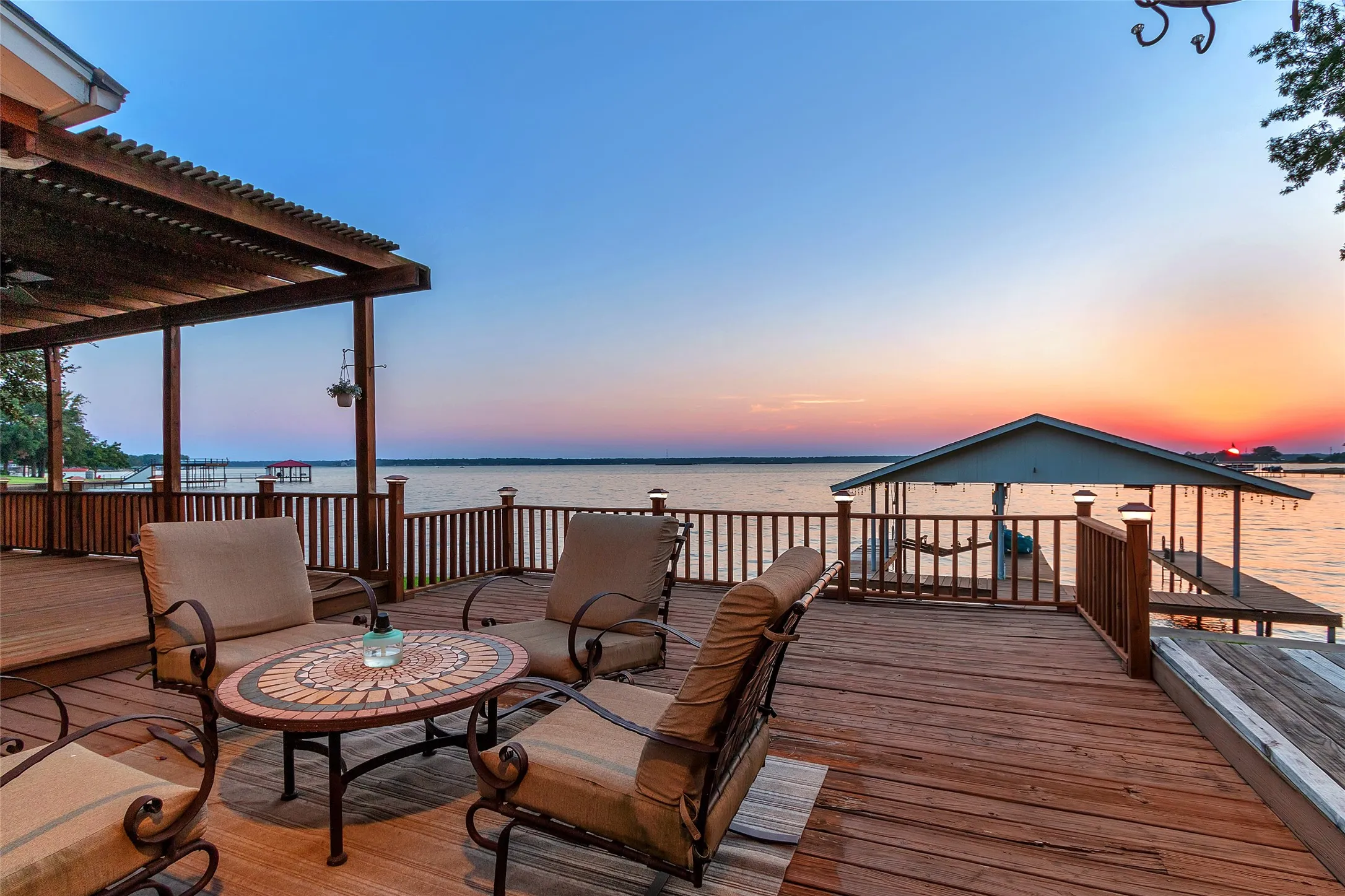 Deck at dusk featuring a pergola and a water view
