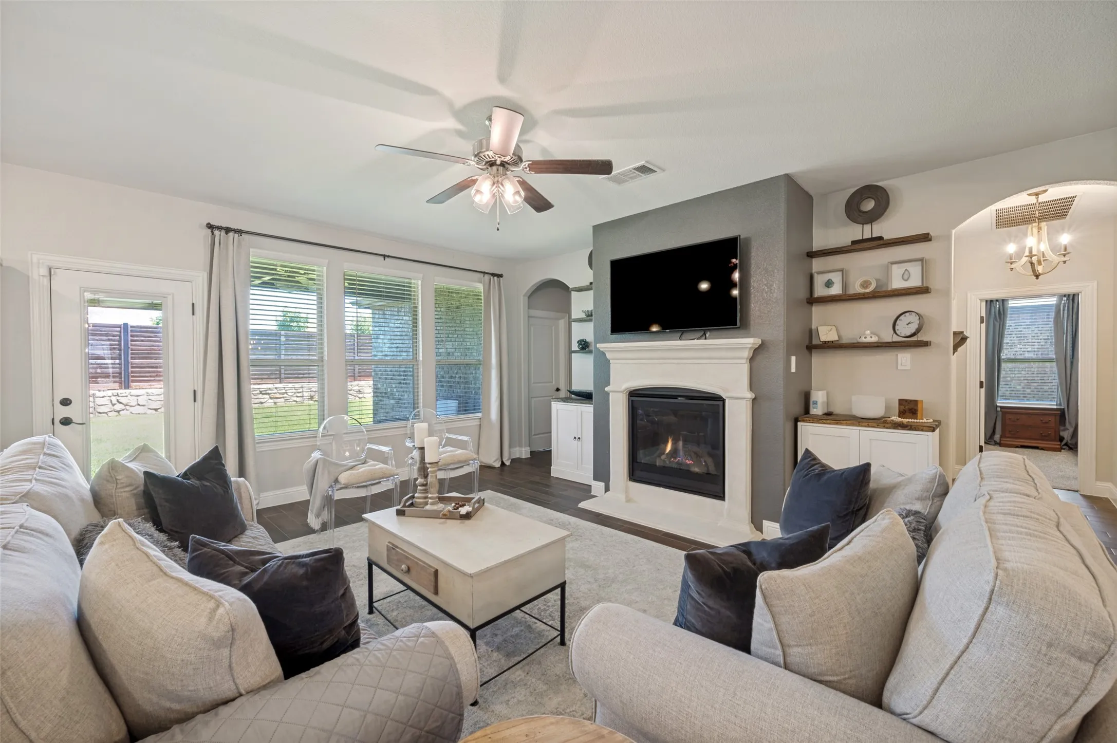 Living area featuring a gas fireplace with a white mantel, dark wood-finish flooring, and multiple windows