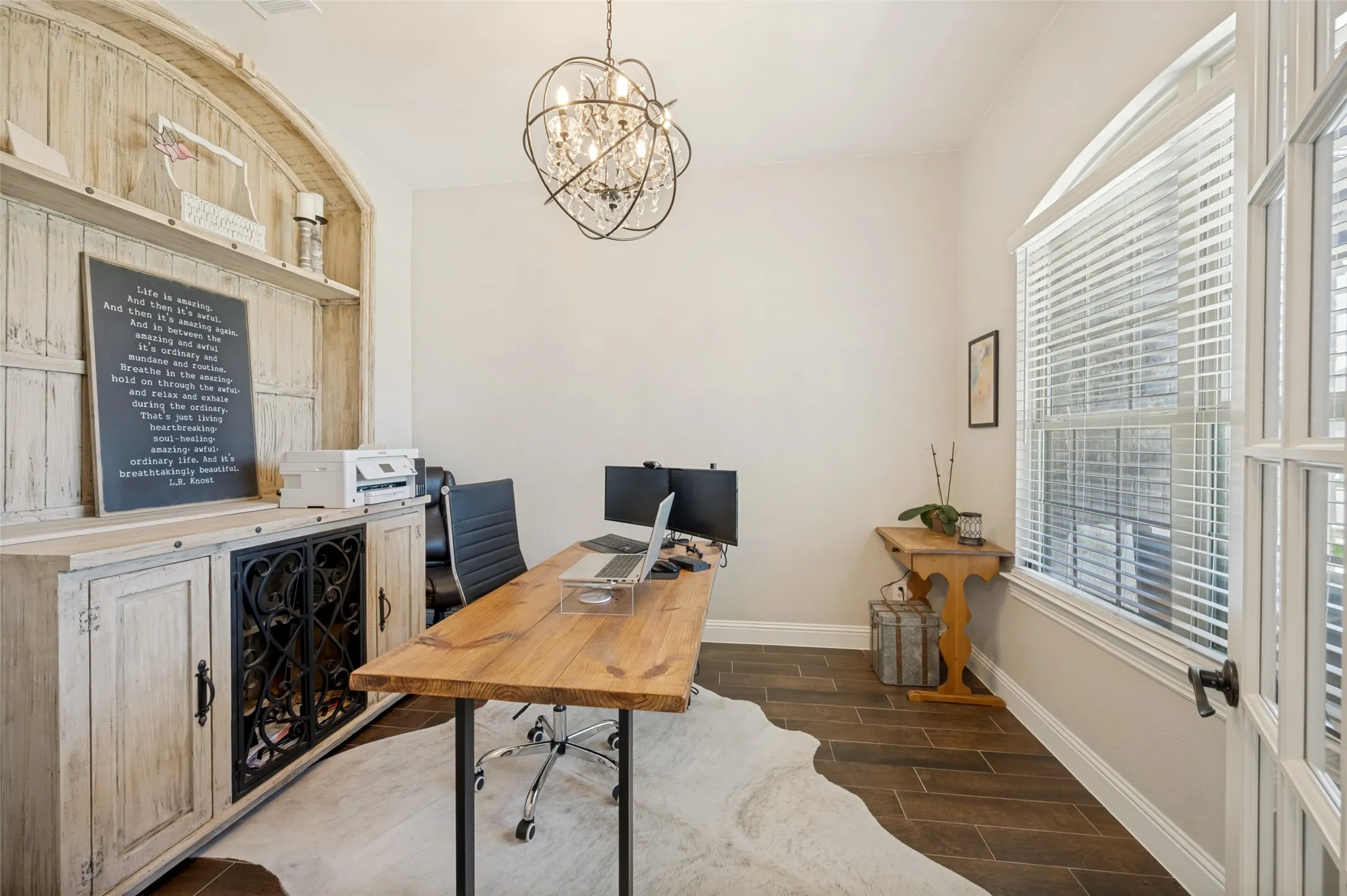 Room featuring wood-finish flooring and a large window with horizontal blinds