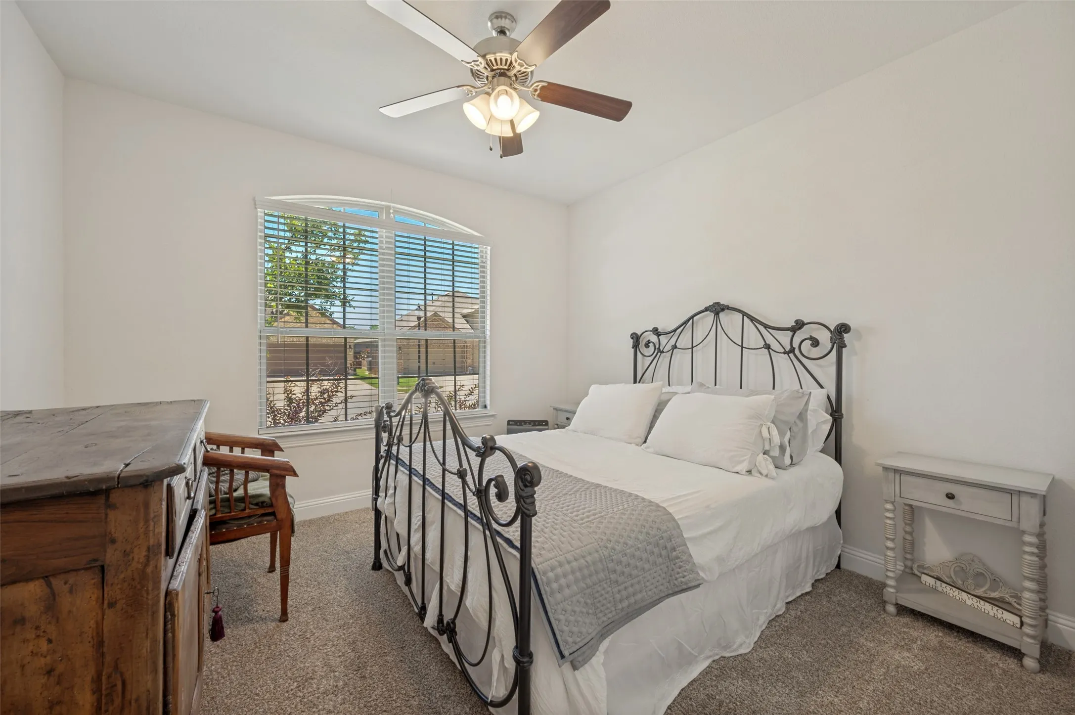 Arched window with blinds, carpet flooring, a ceiling fan with light fixture, and white wall finishes
