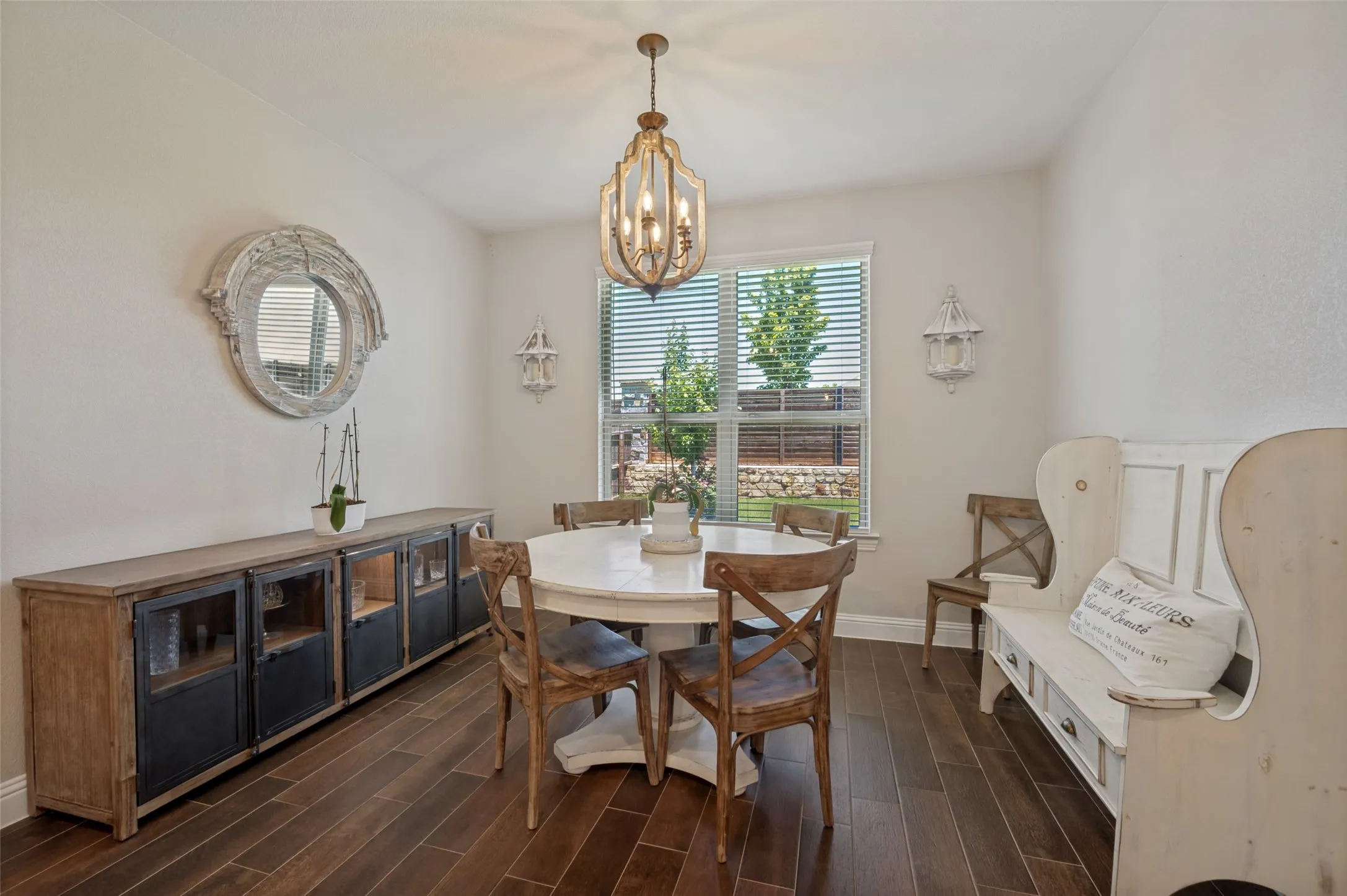 Dining area featuring wood-finish flooring, a contemporary chandelier, and a window with blinds overlooking the exterior