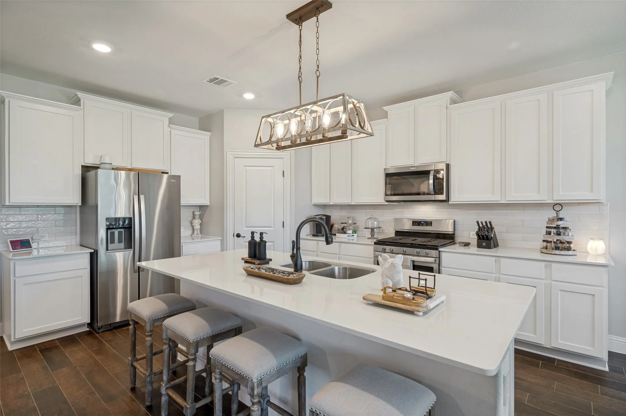 Kitchen featuring white shaker cabinetry, stainless steel appliances, a white subway tile backsplash, and wood-finish flooring