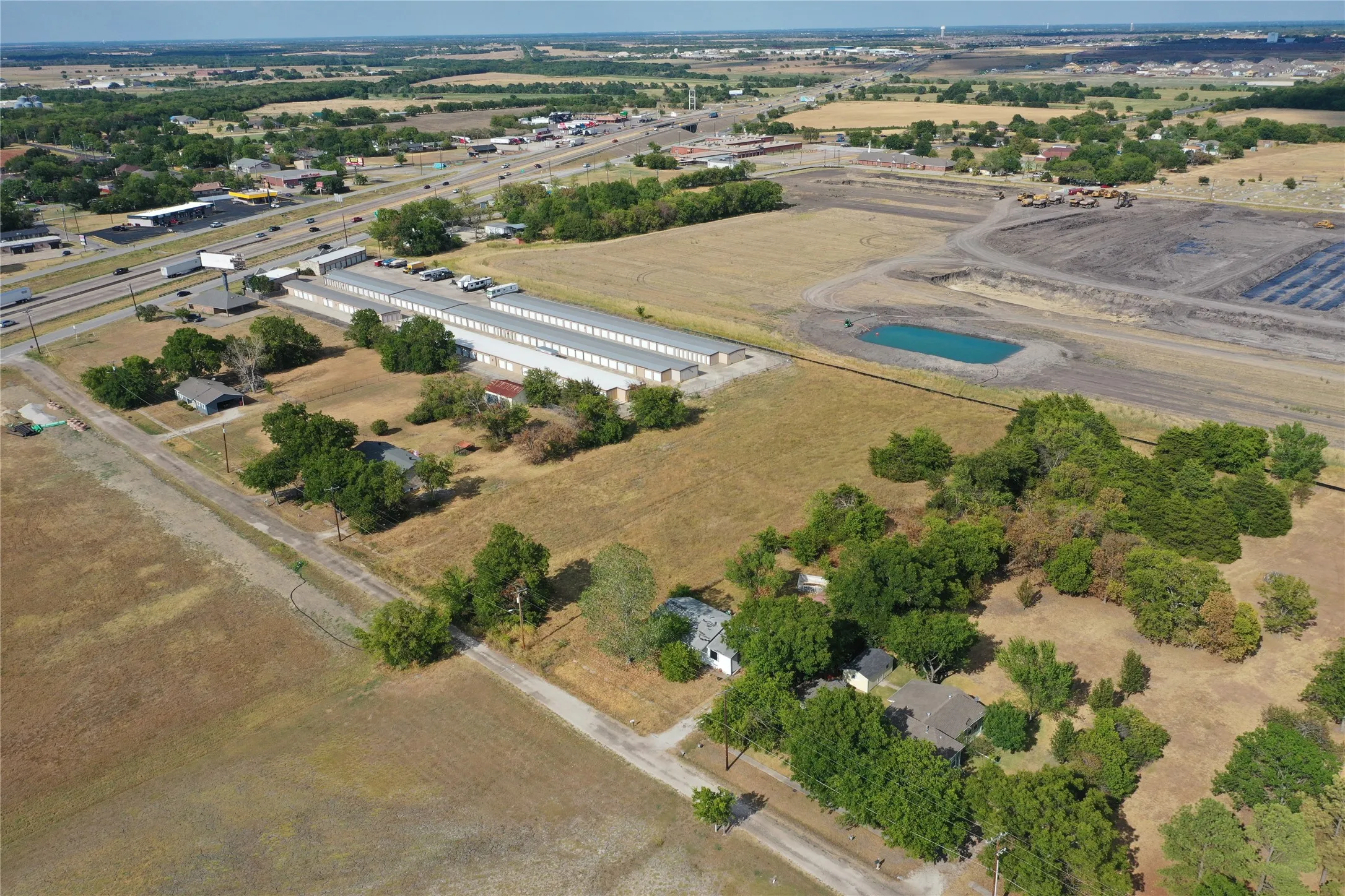 Expansive property featuring multiple structures, mature trees, and open land