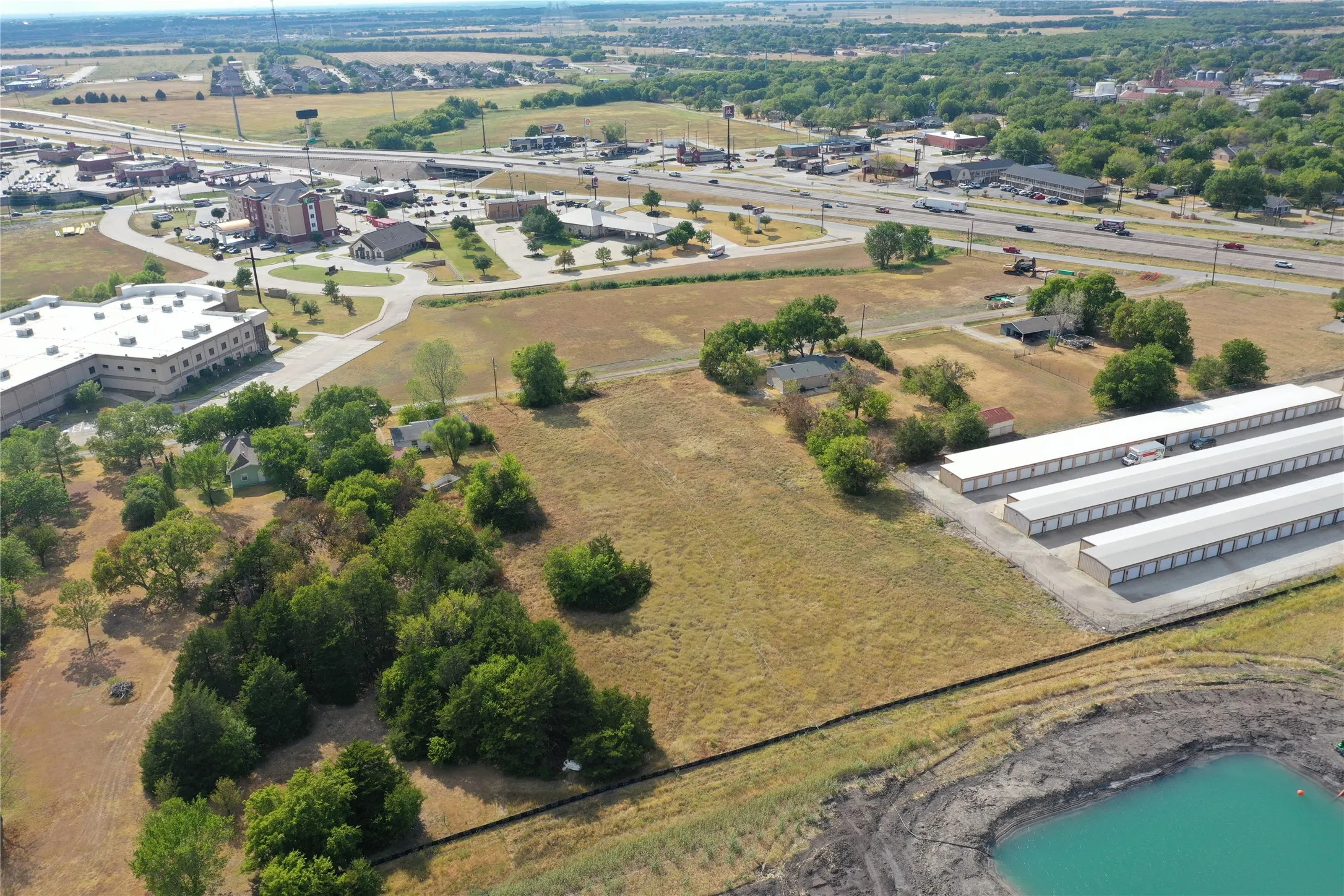 Expansive land parcel featuring existing structures, mature trees, and a pond