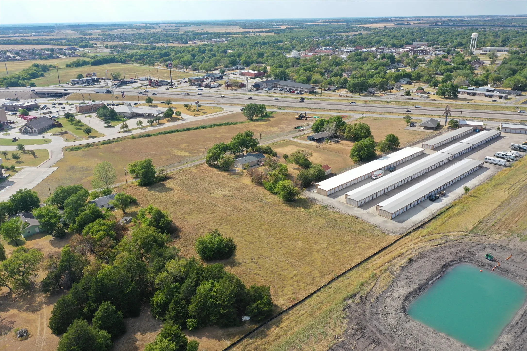 Aerial perspective showcasing a developed storage facility, adjacent commercial properties, and a visible roadway