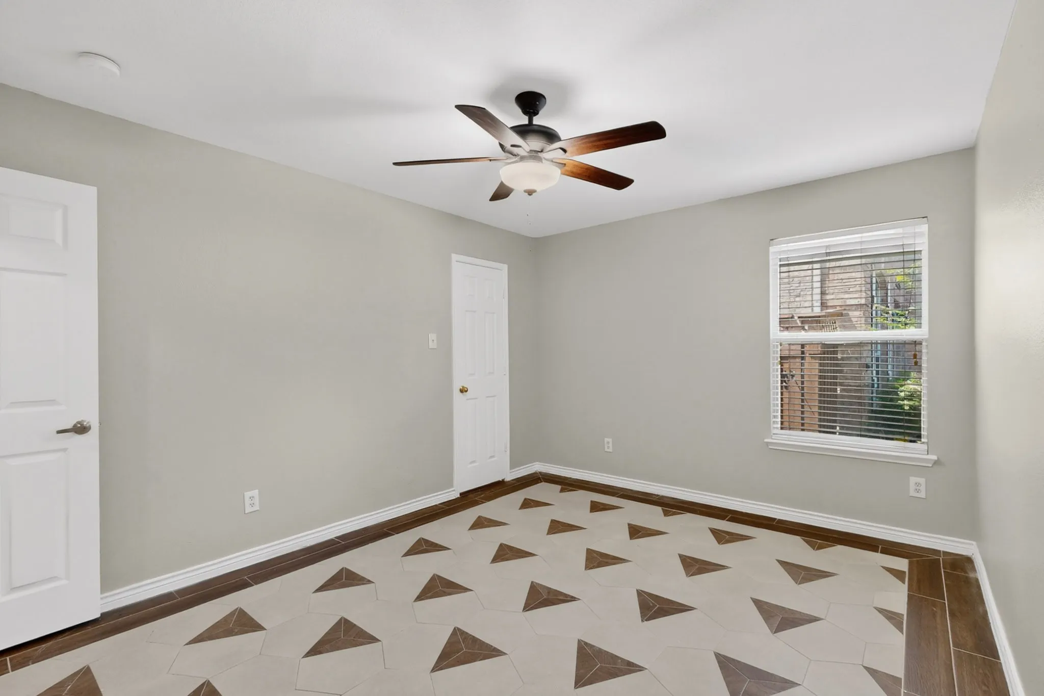Room featuring a geometric-patterned tile floor, light gray wall paint, and white trim