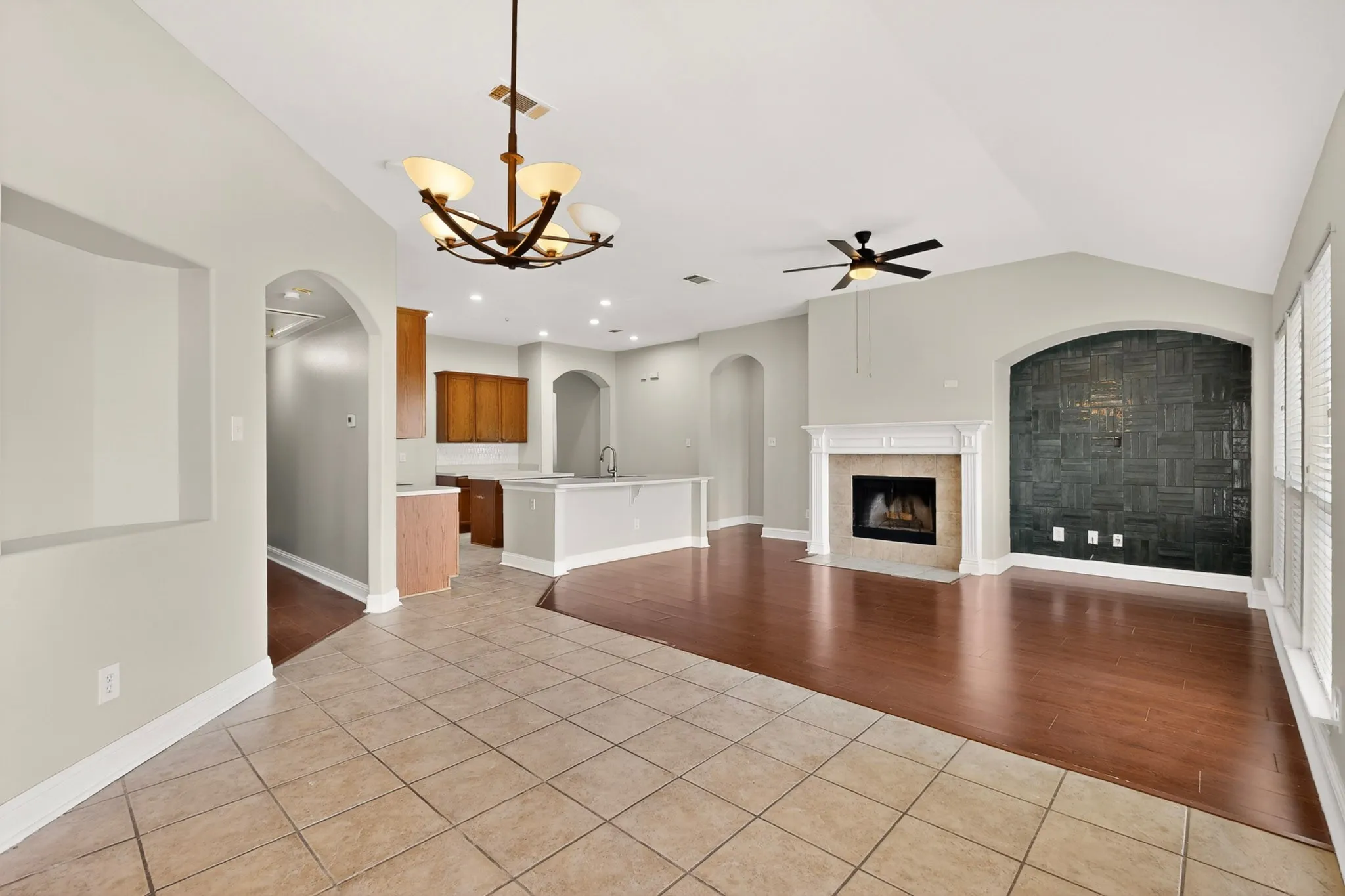 Spacious living area featuring a fireplace with a white mantel, dark wood-finish flooring, and a decorative accent wall