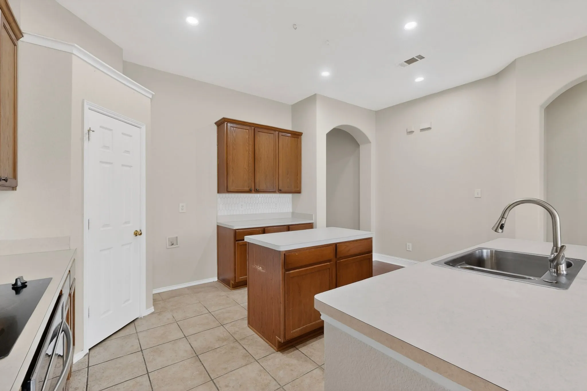 Kitchen featuring light tone cabinetry, light countertops, stainless steel sink with gooseneck faucet, tile flooring, and recessed lighting