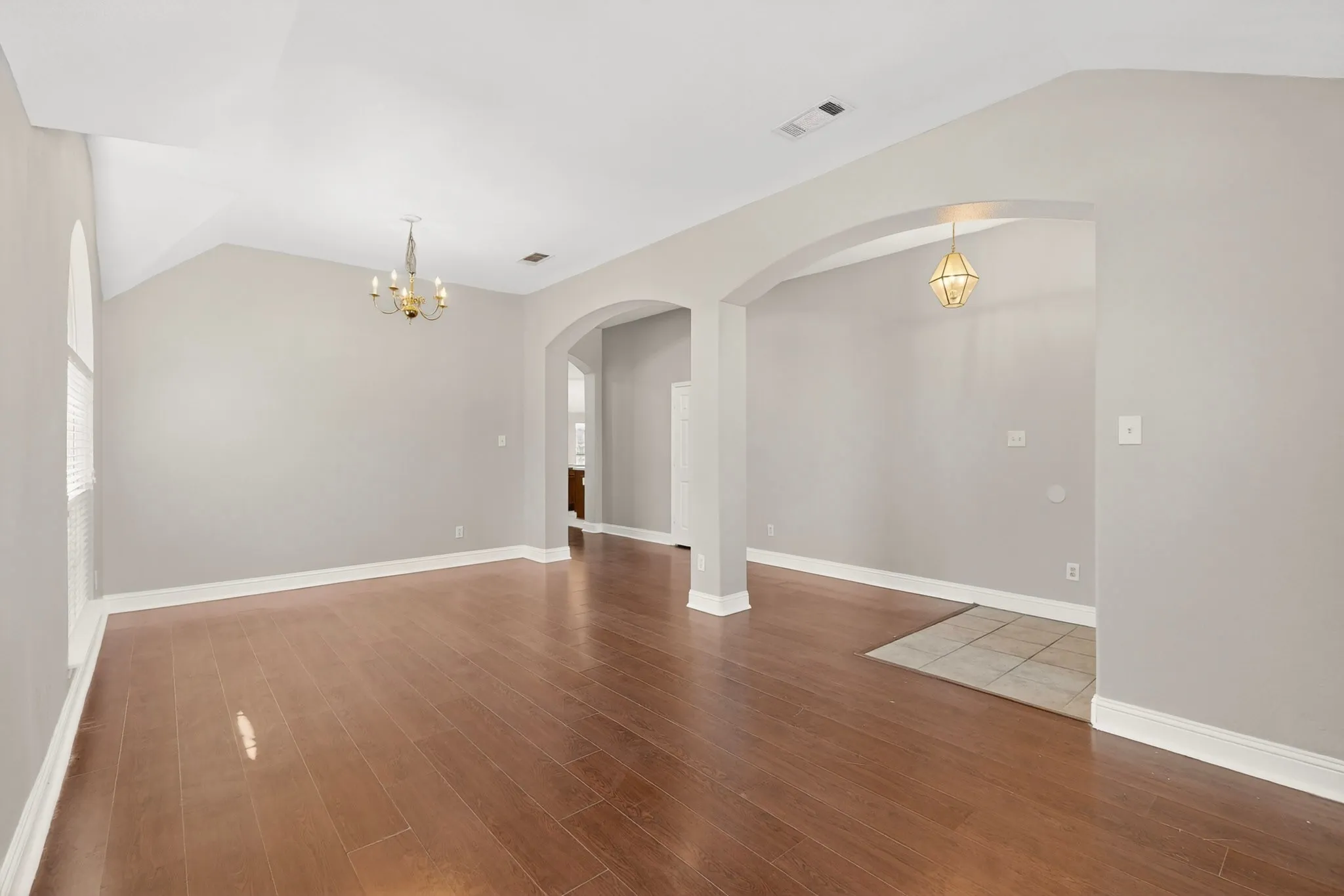 Spacious interior featuring wood-finish flooring, vaulted ceilings, and arched doorways