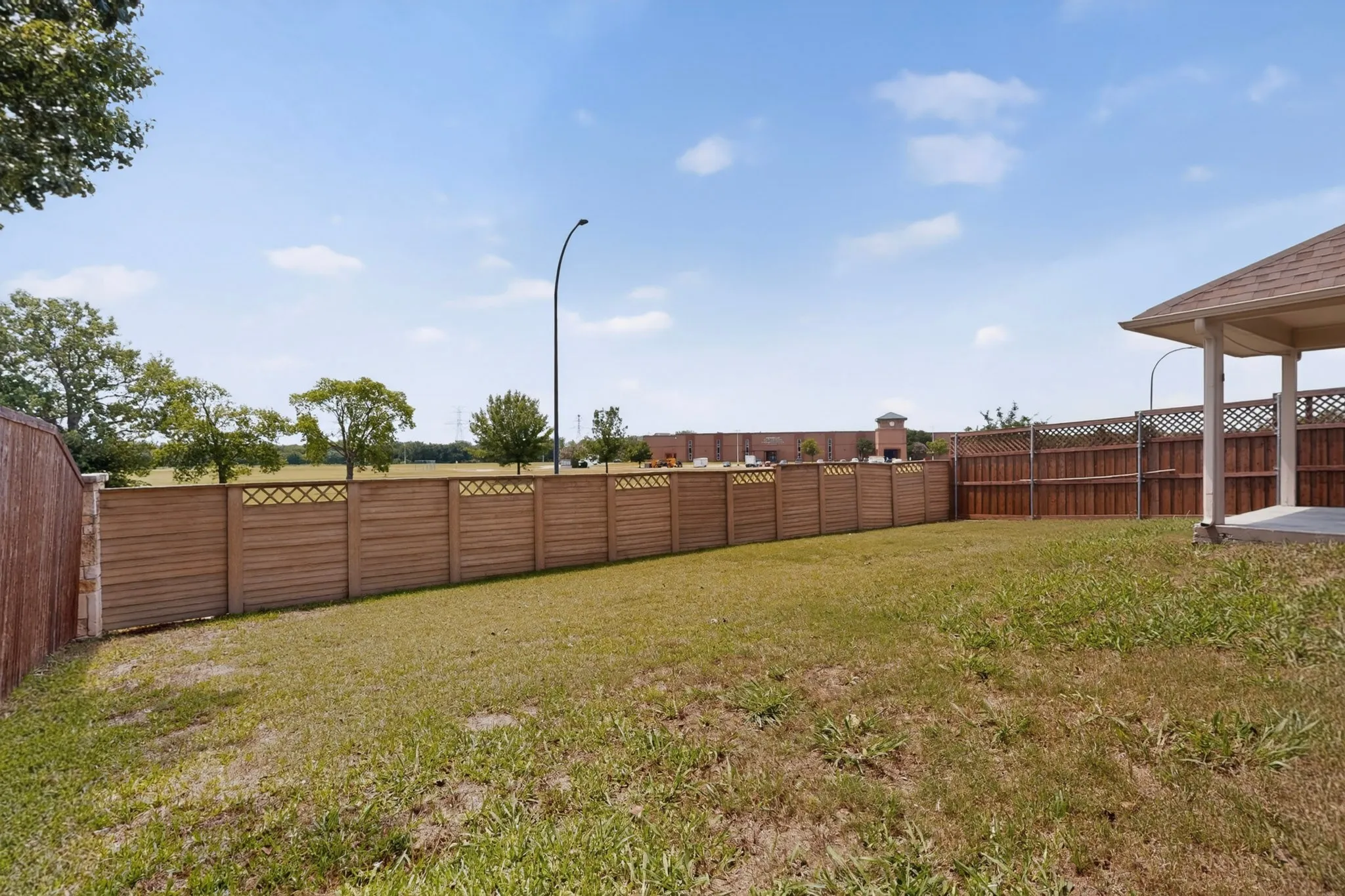 Expansive backyard featuring a combination of horizontal slat and lattice-top privacy fencing